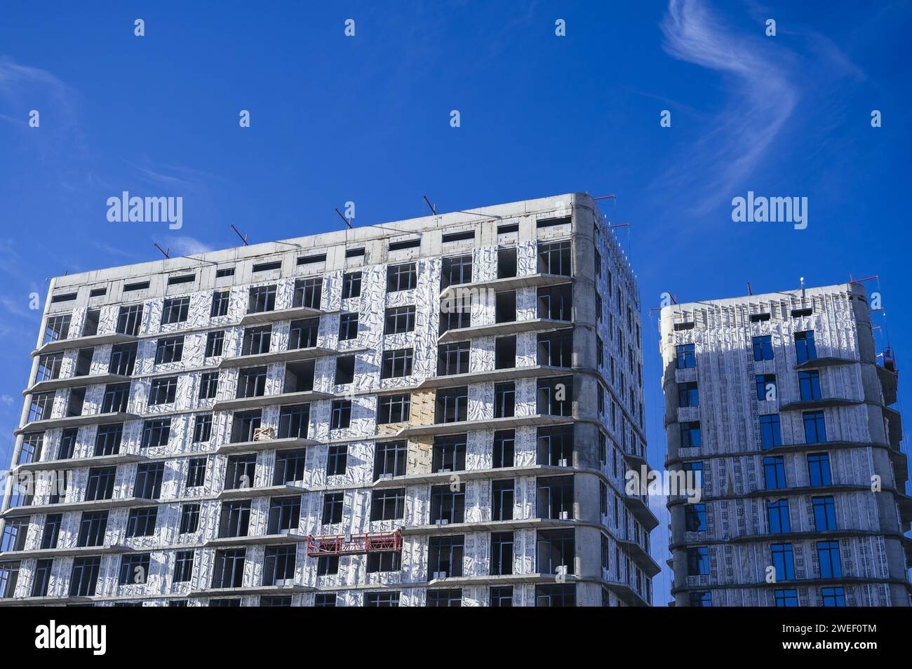SHYMKENT, KAZAKHSAN - 3 GENNAIO 2024: Edificio residenziale in costruzione con pannelli di isolamento termico installati sulla facciata su sfondo blu Foto Stock
