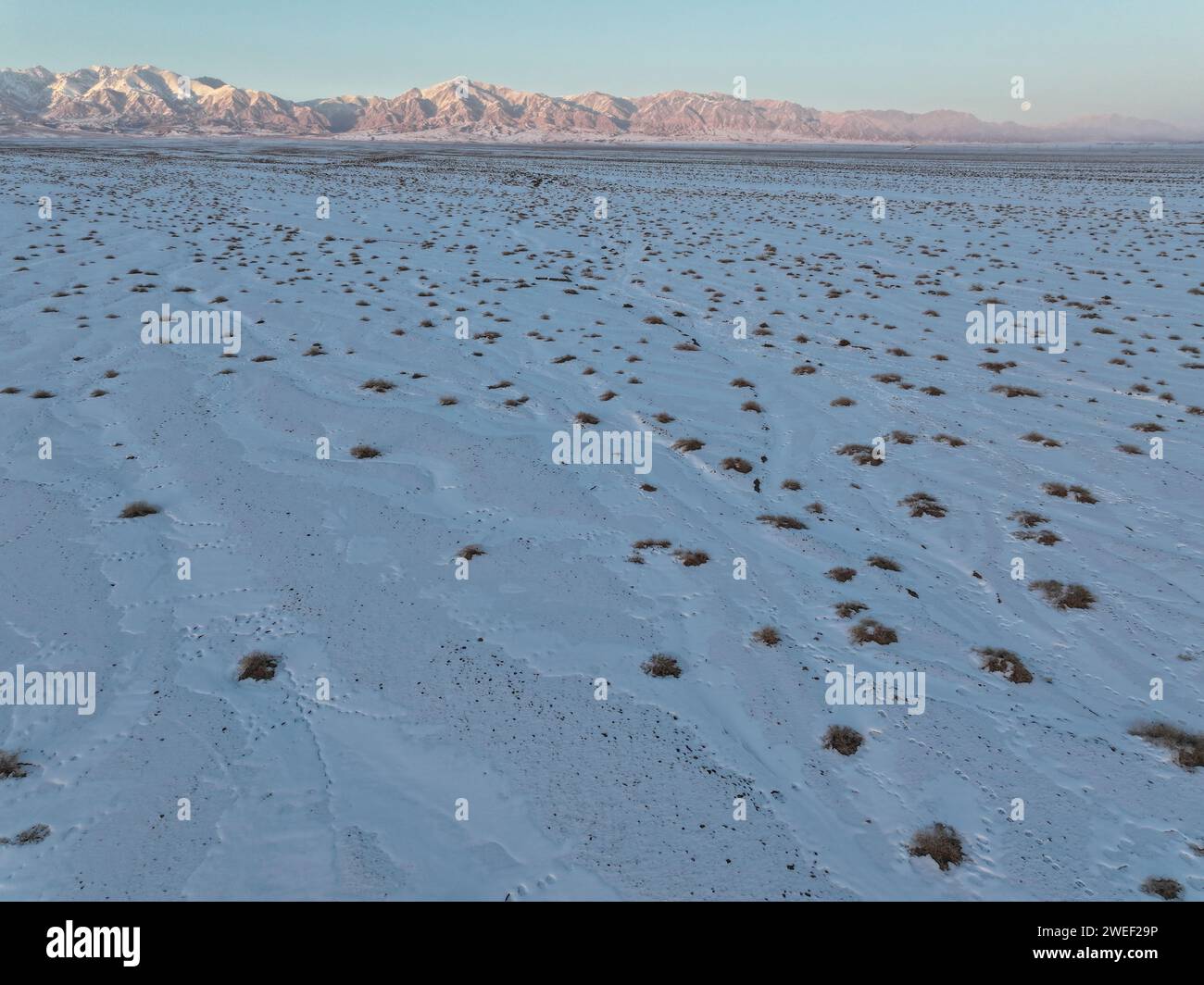 HAMI, CINA - 25 GENNAIO 2024 - Una luna luminosa sorge sui monti Tianshan orientali a Hami, provincia dello Xinjiang, Cina, 25 gennaio 2024. Il primo pieno Foto Stock