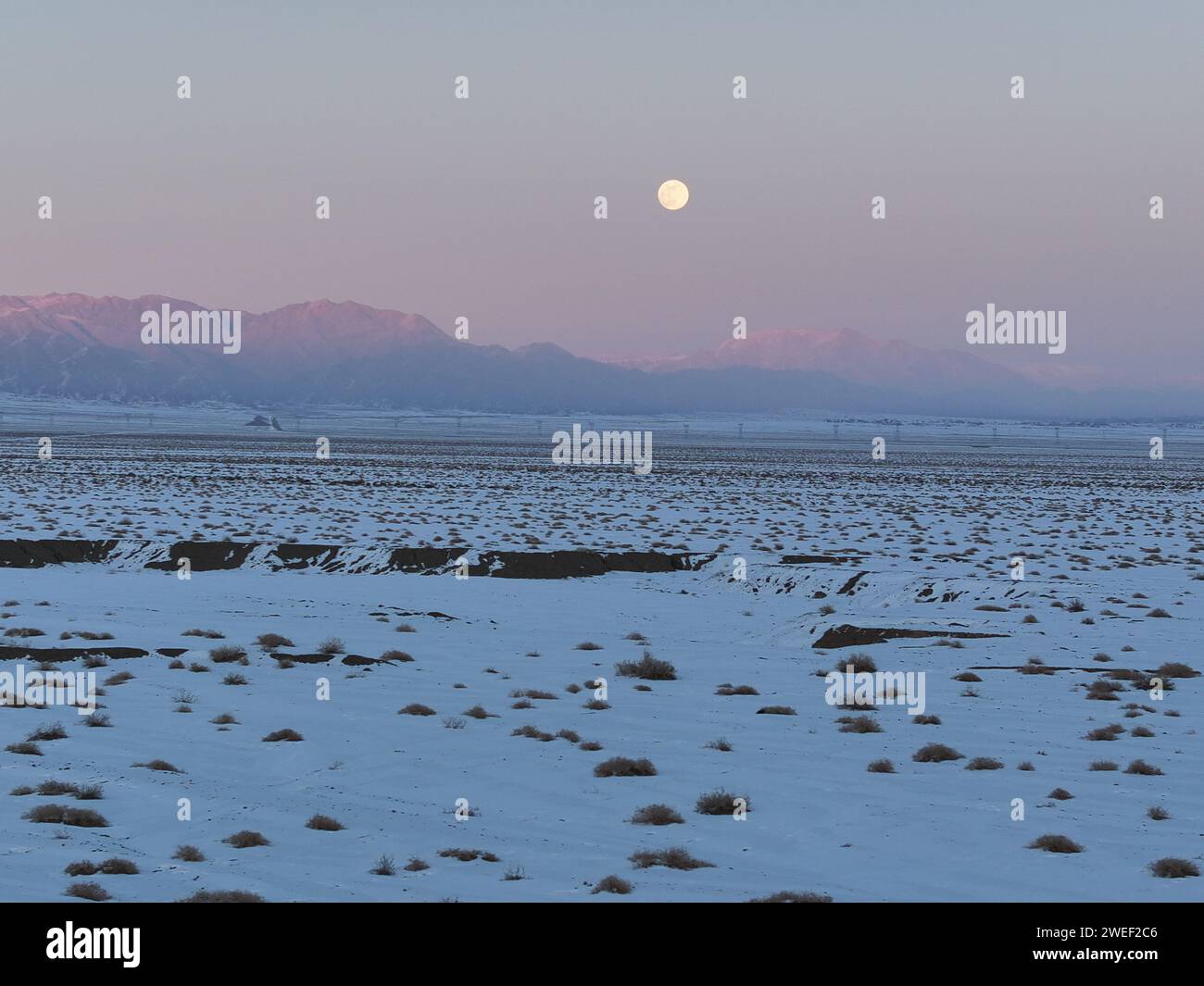 HAMI, CINA - 25 GENNAIO 2024 - Una luna luminosa sorge sui monti Tianshan orientali a Hami, provincia dello Xinjiang, Cina, 25 gennaio 2024. Il primo pieno Foto Stock