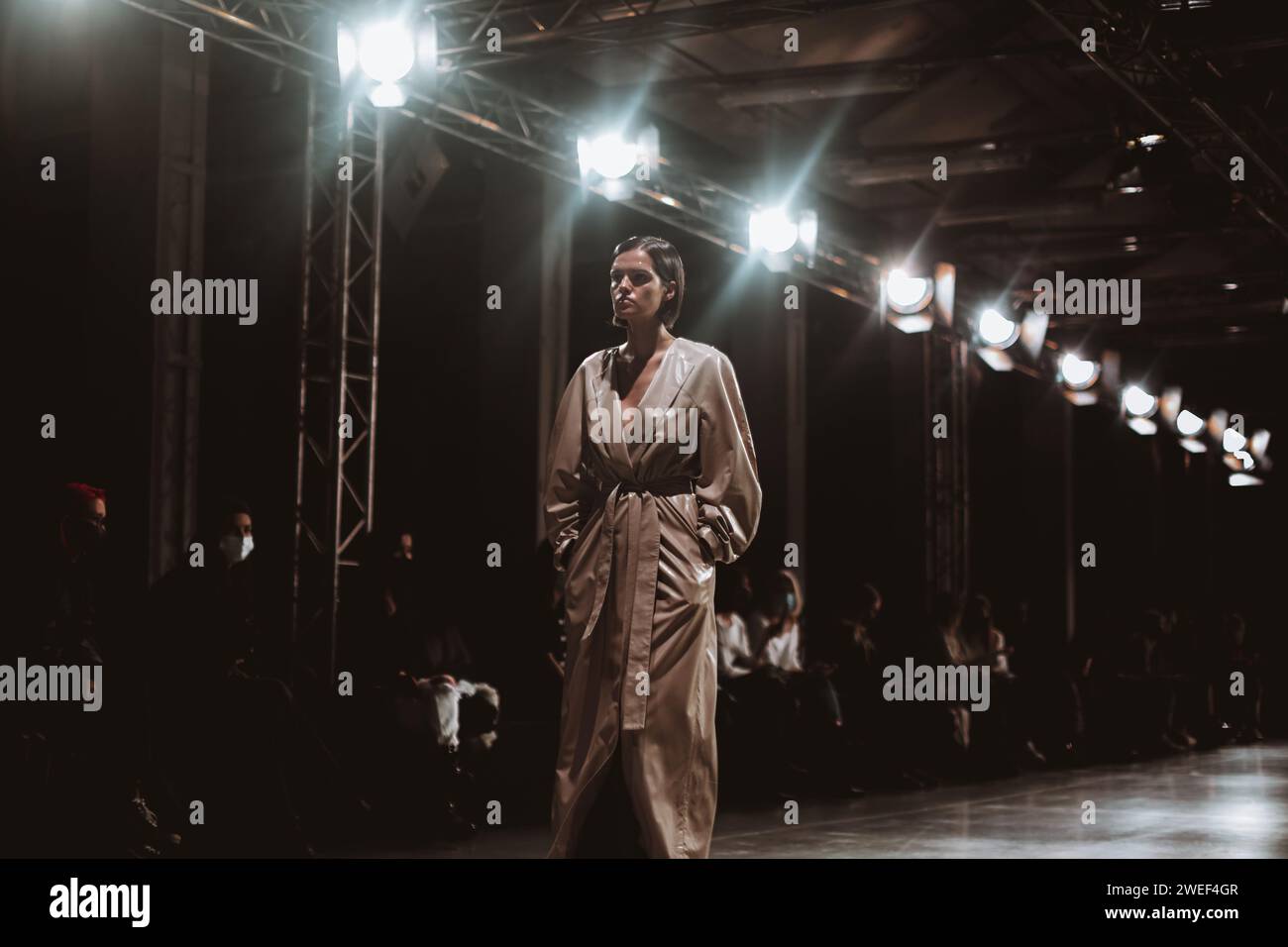 Modello di moda che indossa un lungo cappotto beige stilista che cammina in passerella durante la Fashion Week Foto Stock