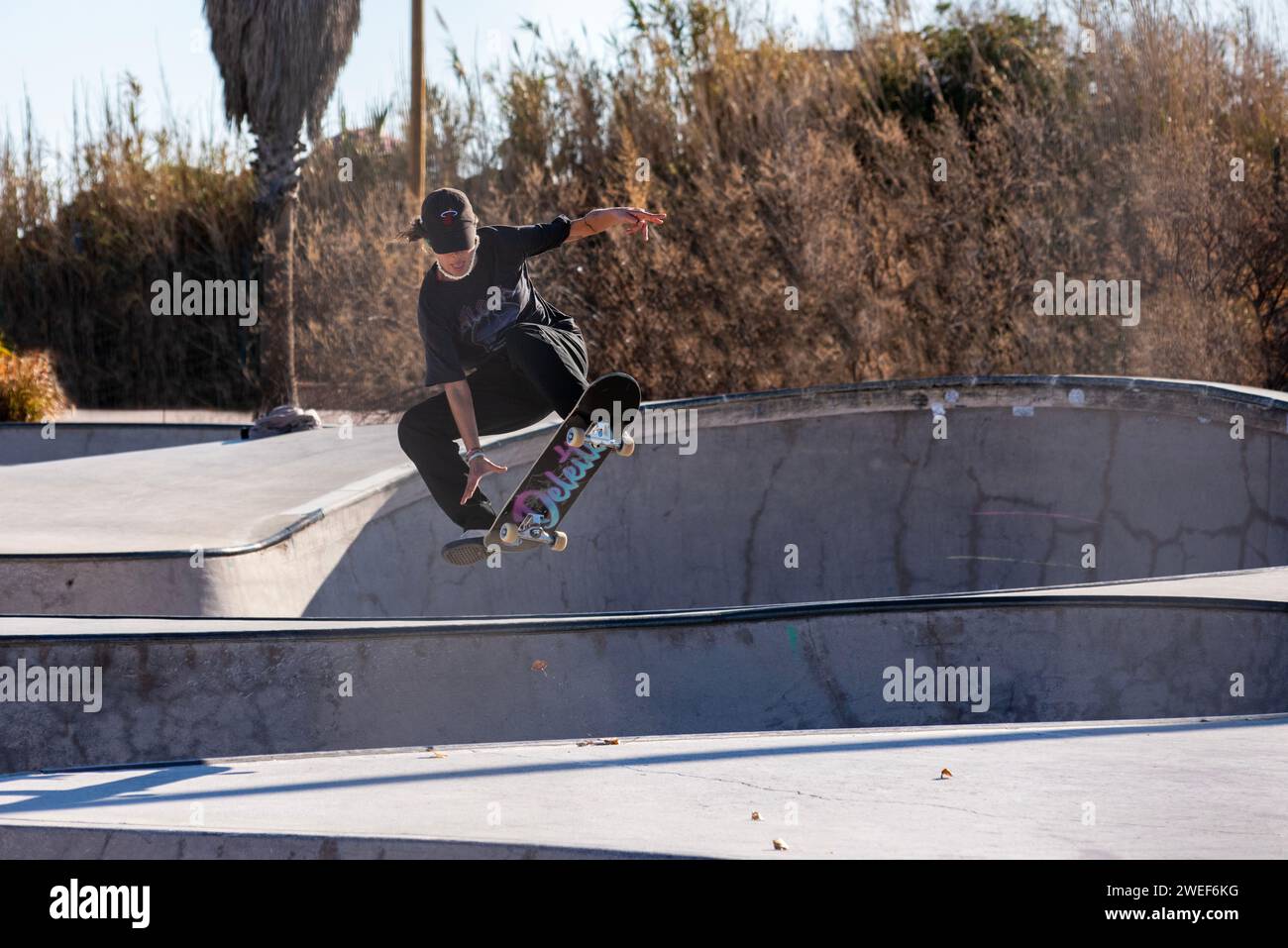 Mosse di skate eleganti: Un elegante skater scivola e salta nell'energia vibrante dello skate Park Foto Stock