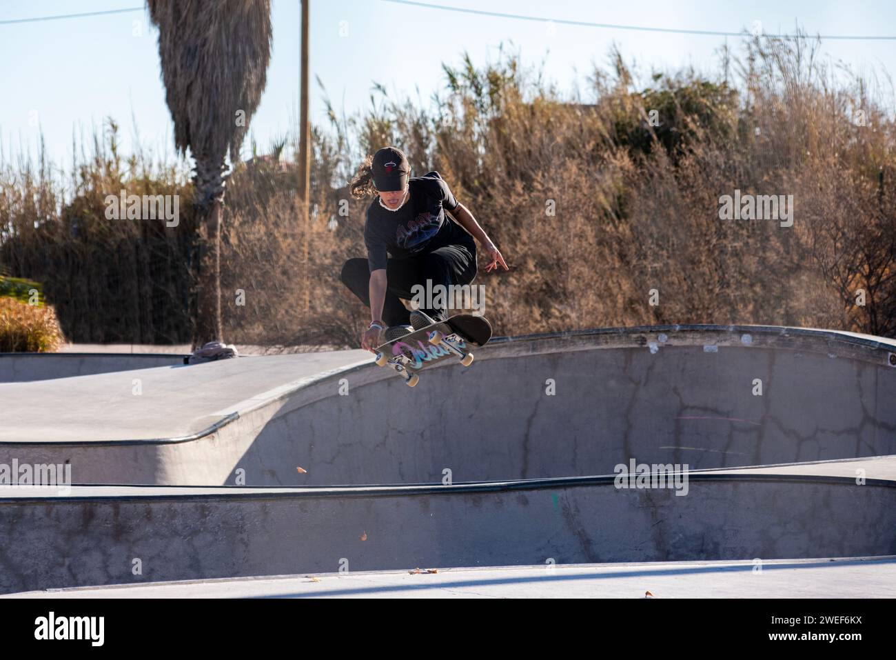 Mosse di skate eleganti: Un elegante skater scivola e salta nell'energia vibrante dello skate Park. Foto Stock