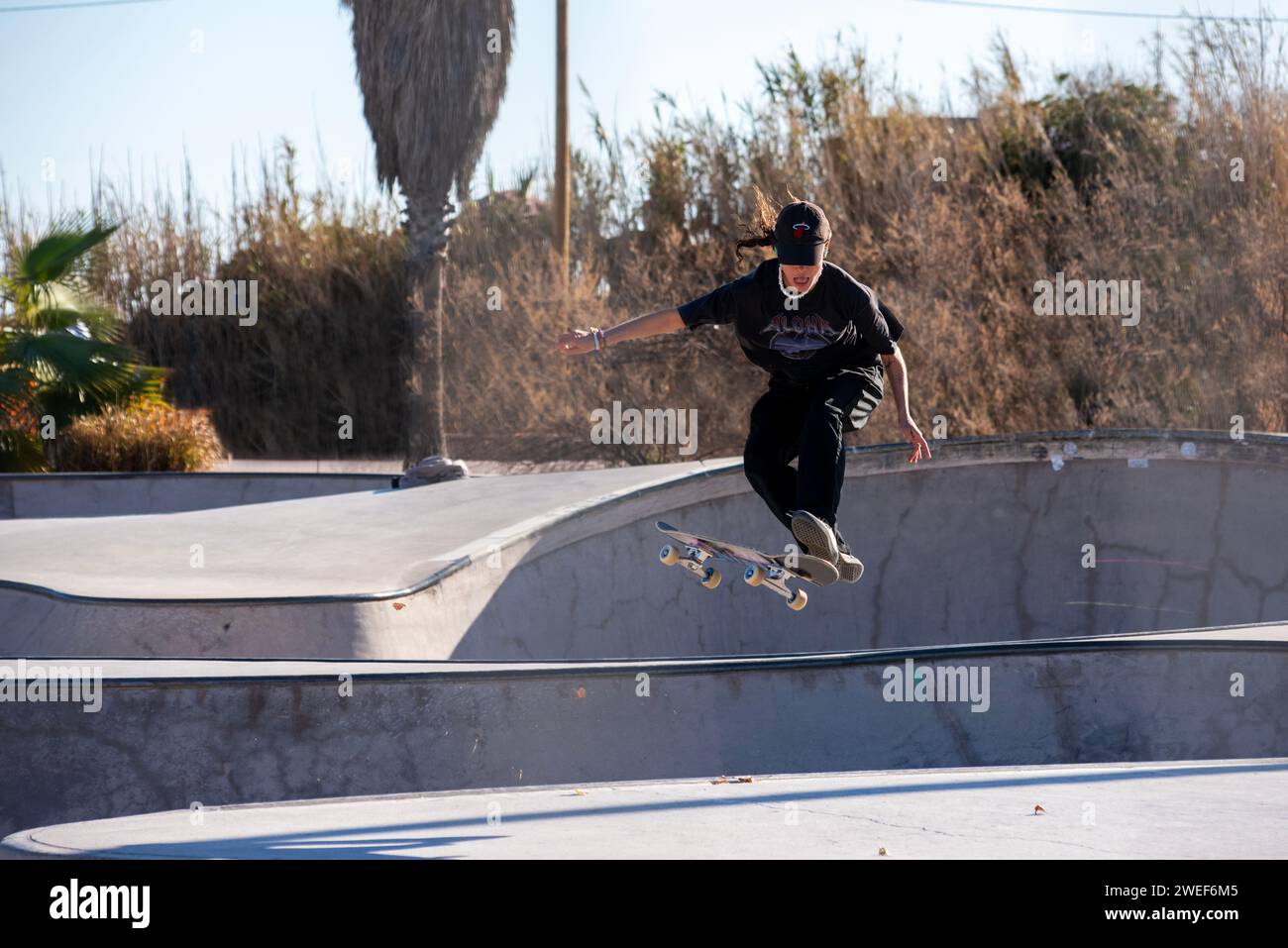 Mosse di skate eleganti: Un elegante skater scivola e salta nell'energia vibrante dello skate Park Foto Stock