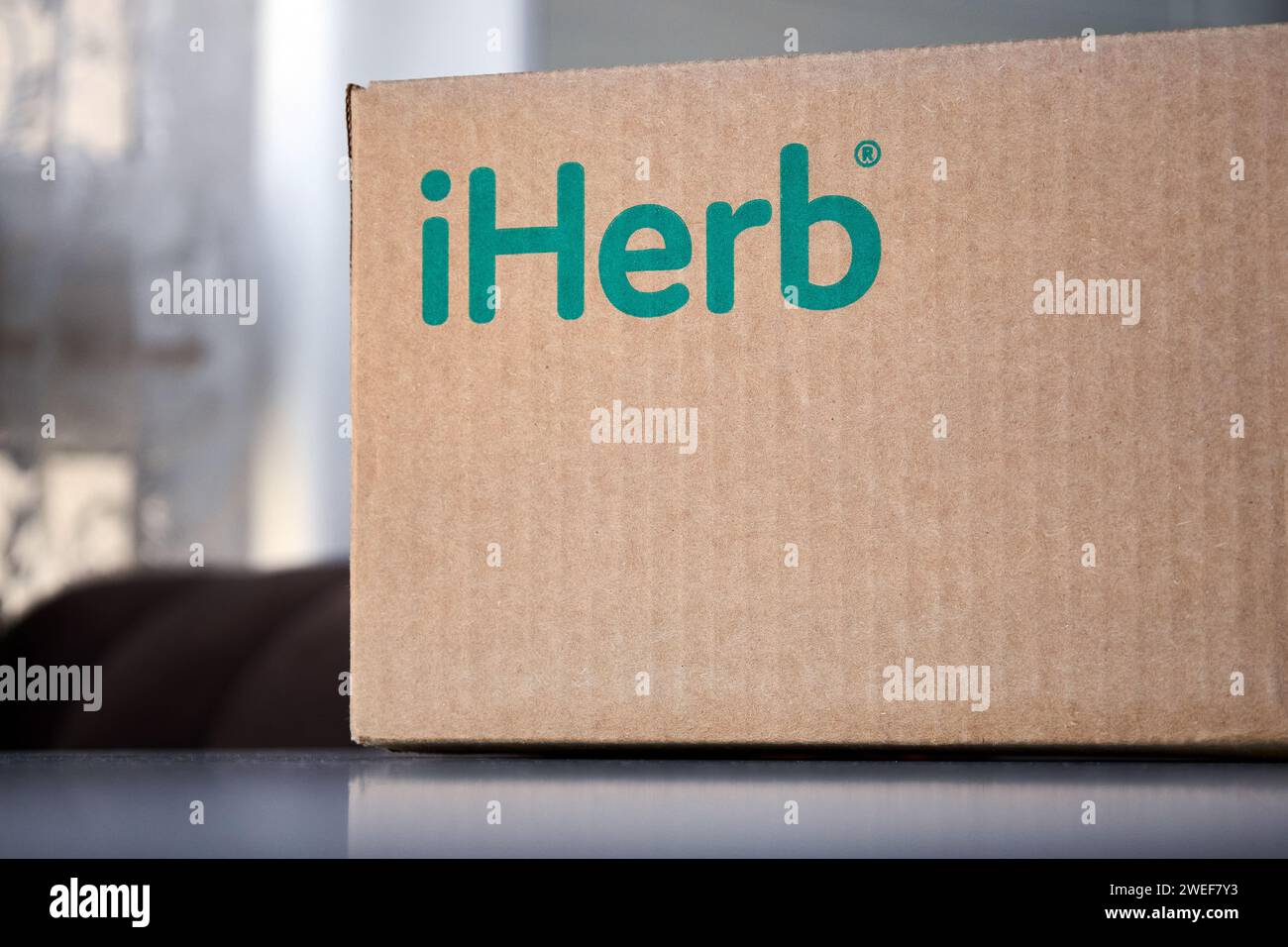 Scatola in cartone marrone con logo verde iHerb a casa, sul tavolo. Ordini online, acquisti, acquisto di vitamine e cosmetici. Ricezione della p Foto Stock