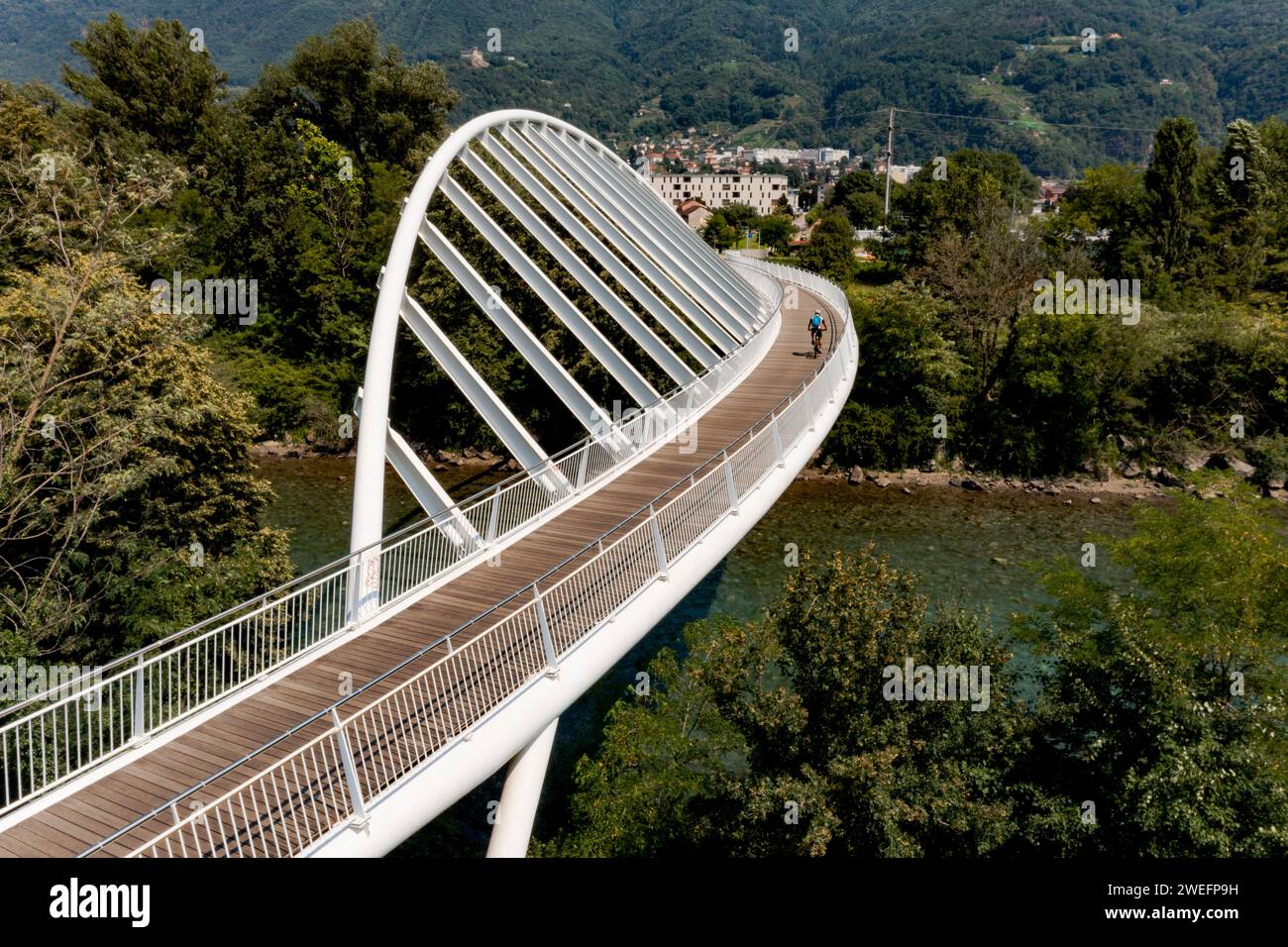Ponte pedonale su un piccolo fiume svizzero, il Ticino. In estate, la passerella pedonale è in mezzo alla natura con una forma molto moderna Foto Stock