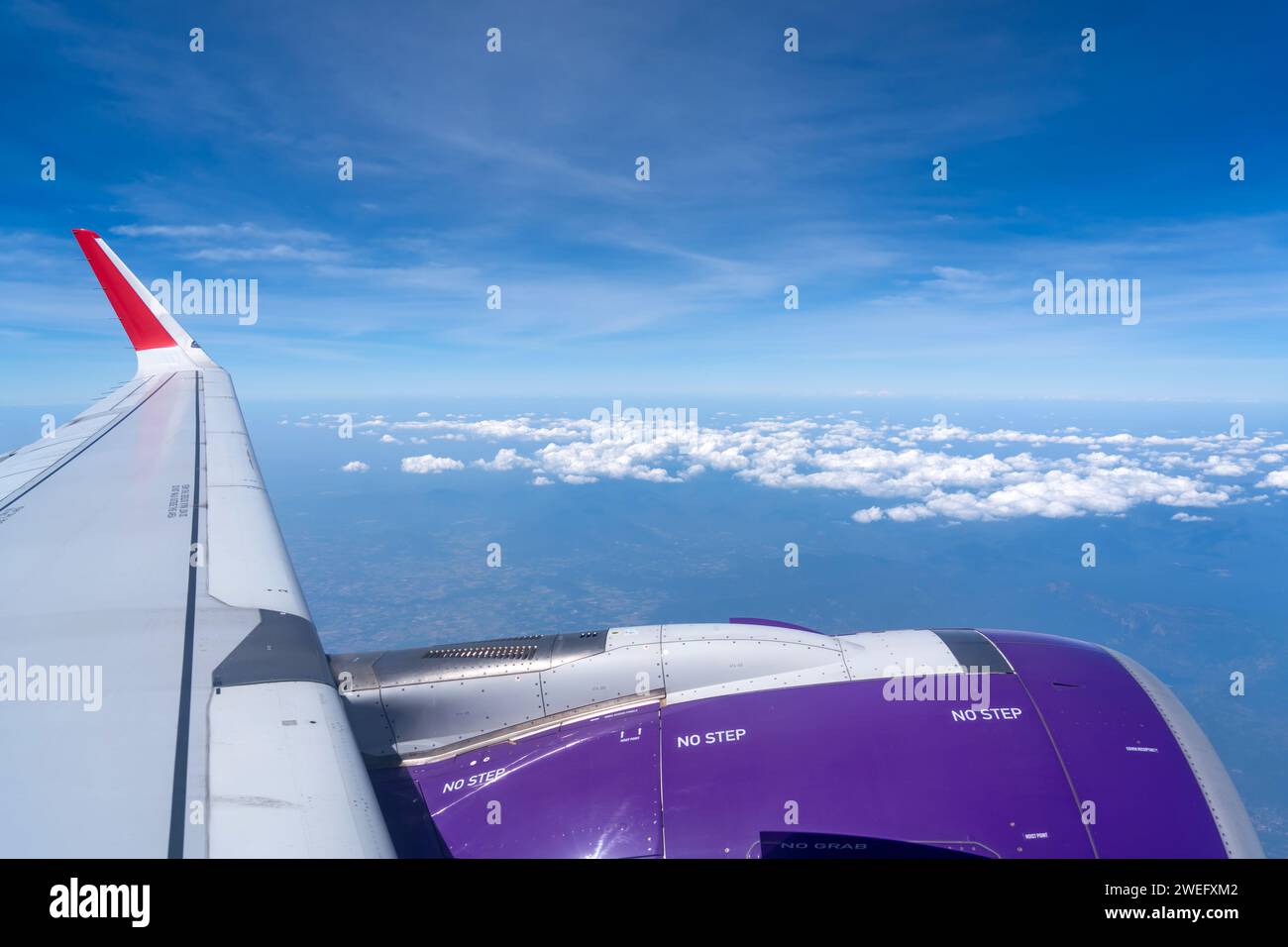 Effetto turbolenza, agitazione delle ali, vibrazioni della fusoliera degli aerei. Guardando attraverso gli aerei a finestra durante il volo nell'ala con un bel cielo blu. Foto Stock