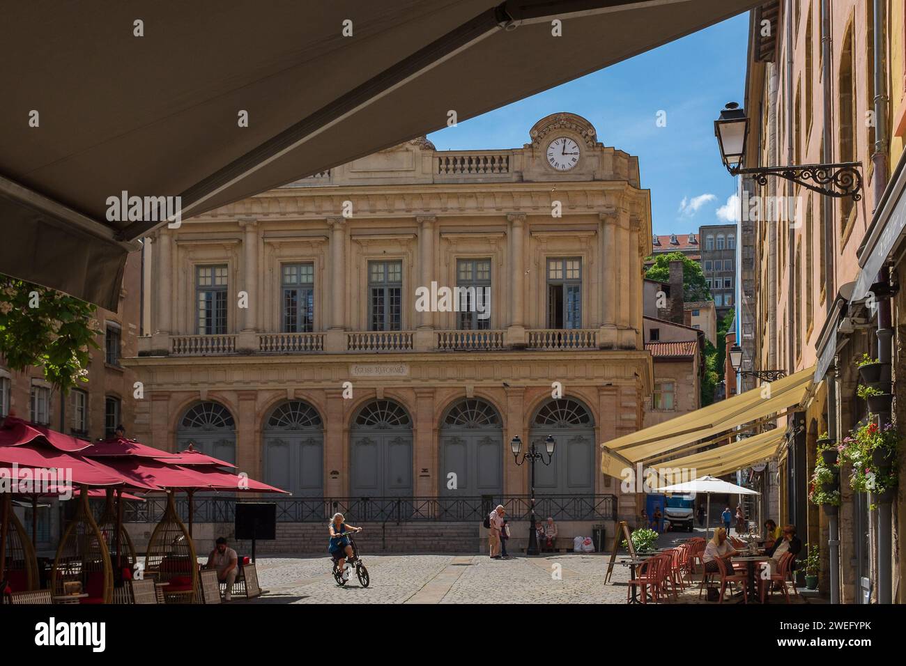 Lione, Francia, 2023. I turisti seduti nei caffè Place du Change nel quartiere Saint-Paul, con la chiesa riformata del Tempio del cambiamento sullo sfondo Foto Stock