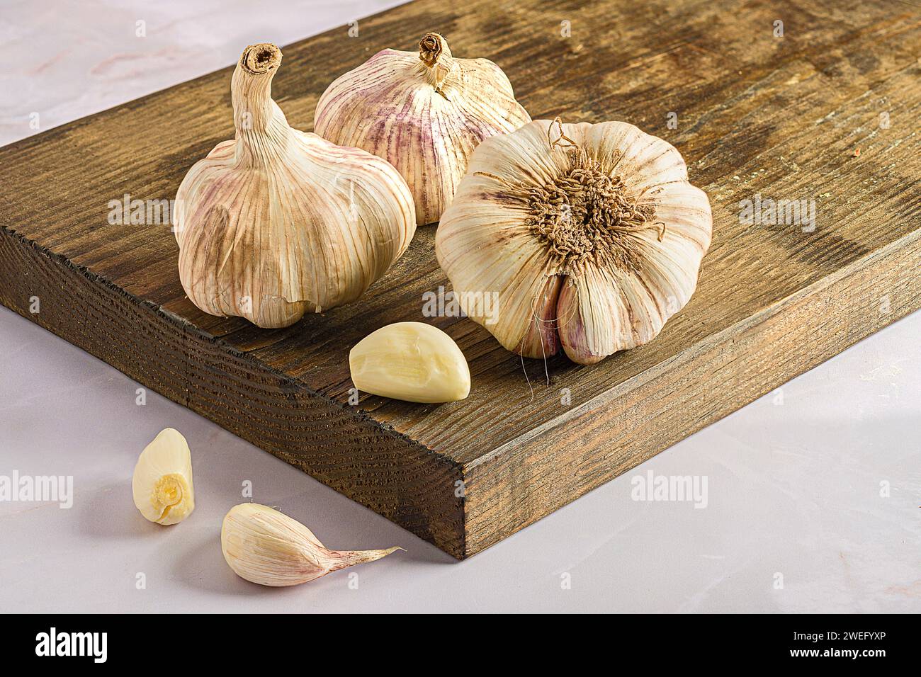 Gli spicchi d'aglio e le bucce su un tagliere di legno Foto Stock