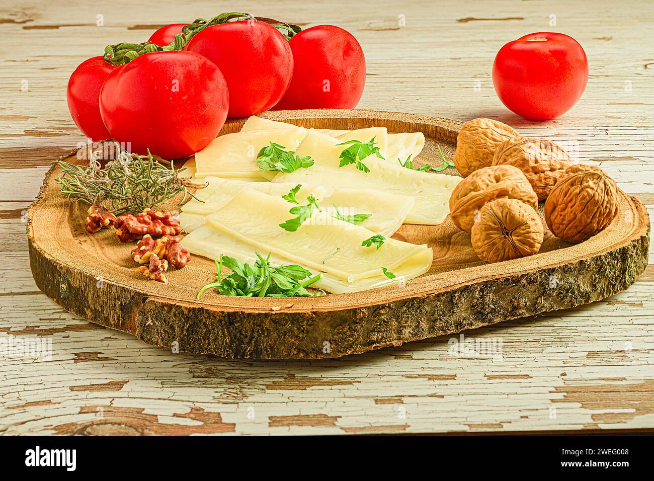 Un piatto con formaggio, pomodori, noci ed erbe aromatiche disposti su un tavolo di legno Foto Stock