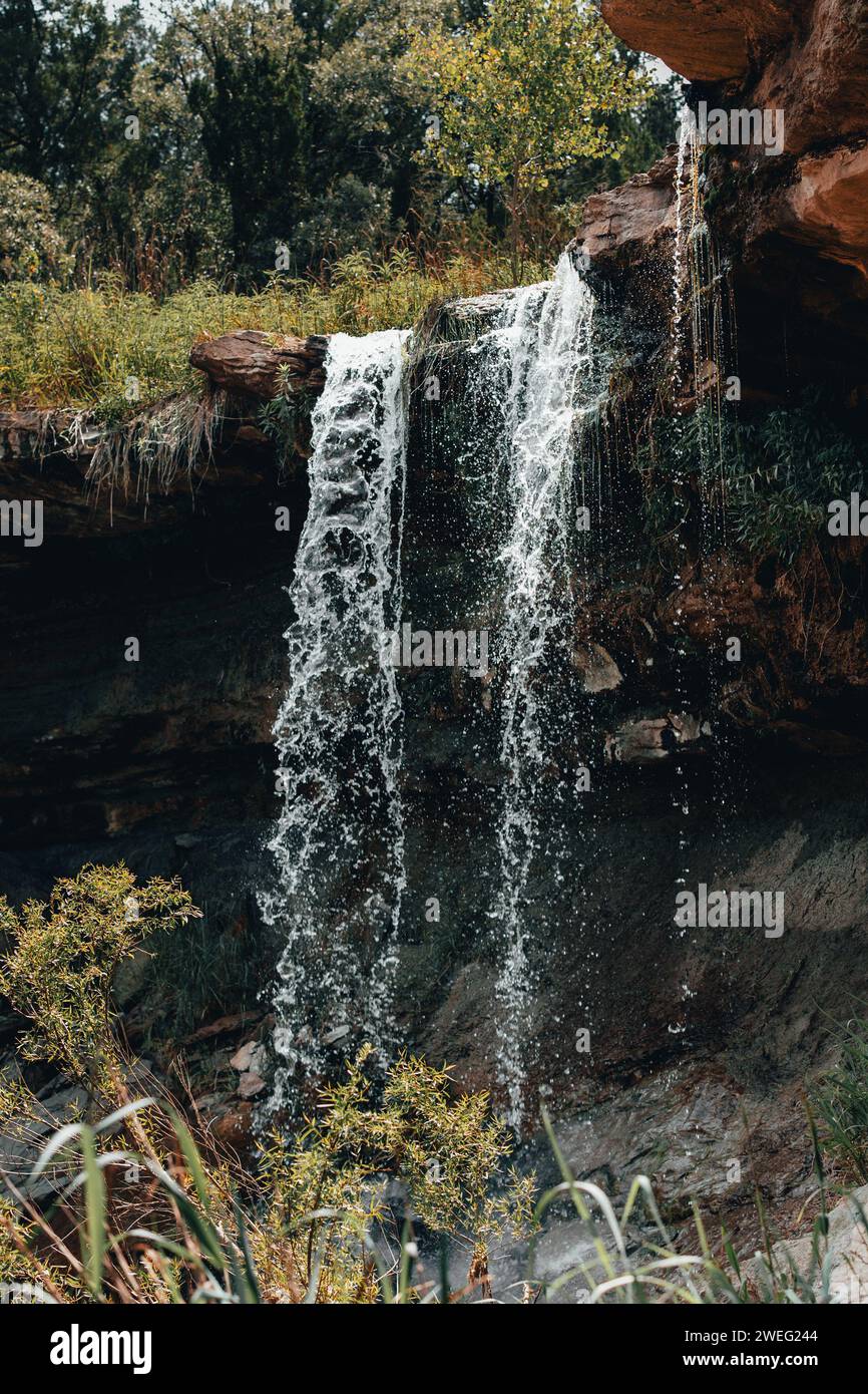 Cascata che cade nella scogliera con alberi lontani Foto Stock