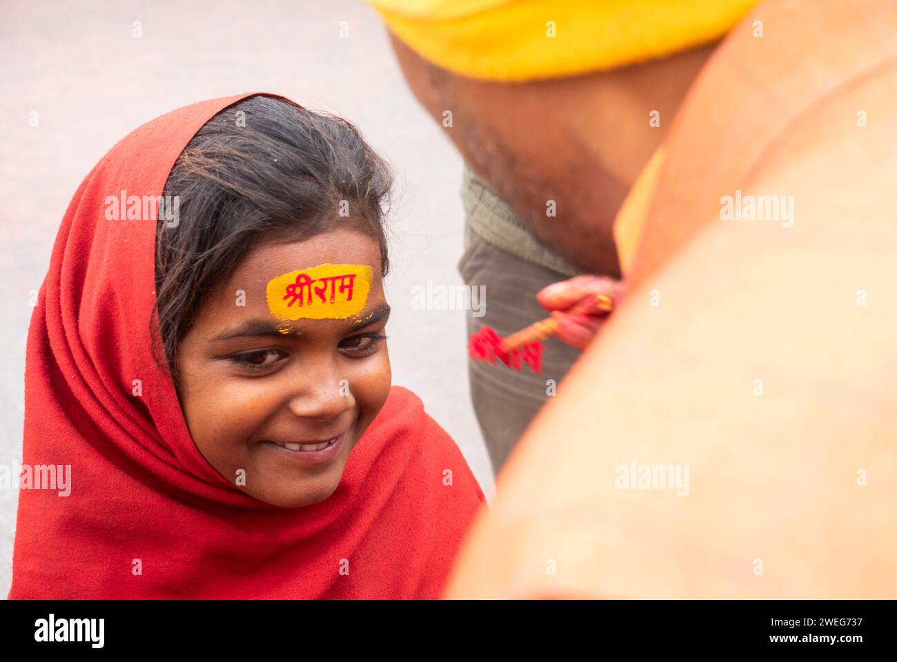 Ai bambini viene dipinto il nome di Lord RAM sulla fronte, alla vigilia della cerimonia di consacrazione del tempio RAM, ad Ayodhya, Uttar Pradesh, India, il 22 gennaio 2024. Foto Stock