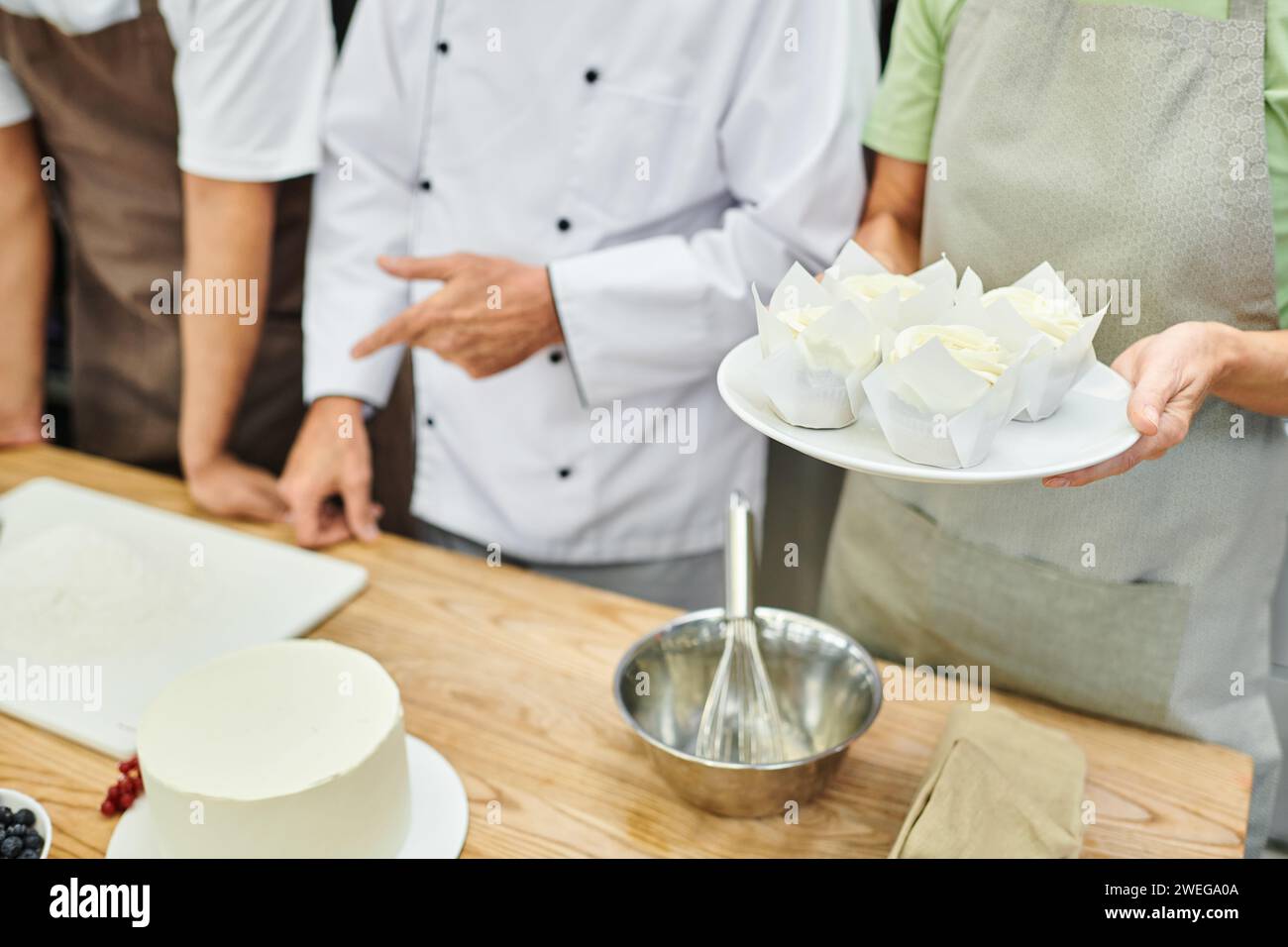 vista corta dello chef maturo che mostra come cuocere ai suoi studenti multiculturali, corsi di cucina Foto Stock