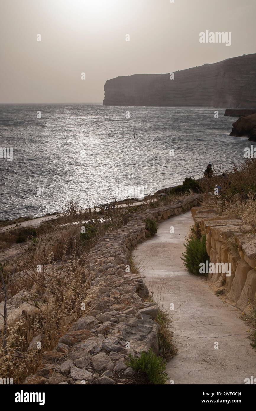 Un sentiero roccioso conduce a una splendida spiaggia al tramonto Foto Stock