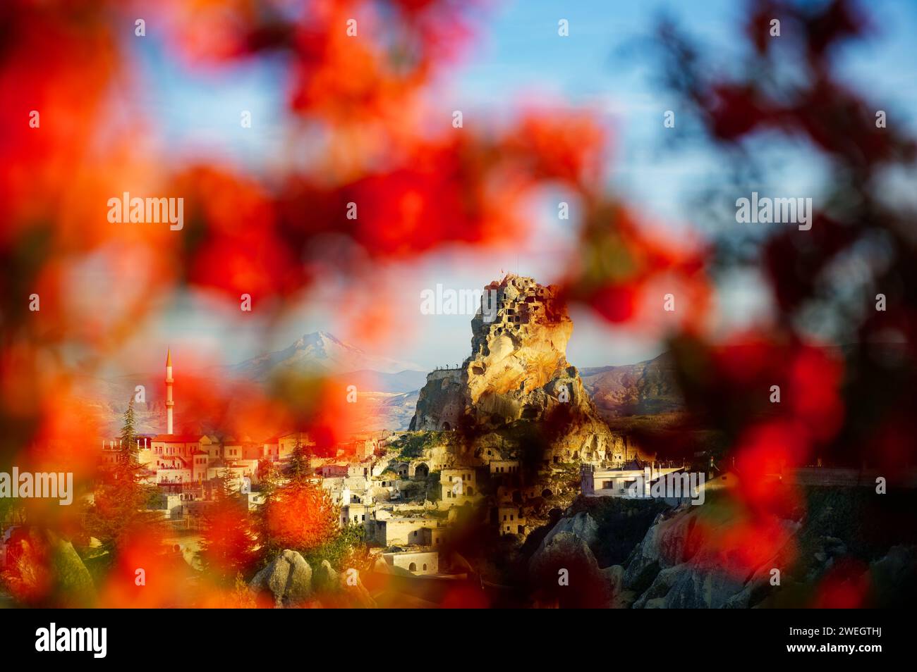 Vista del castello di Ortahisar tra le foglie rosse della Cappadocia, Turchia. Il Monte Erciyes innevato è visibile sullo sfondo Foto Stock