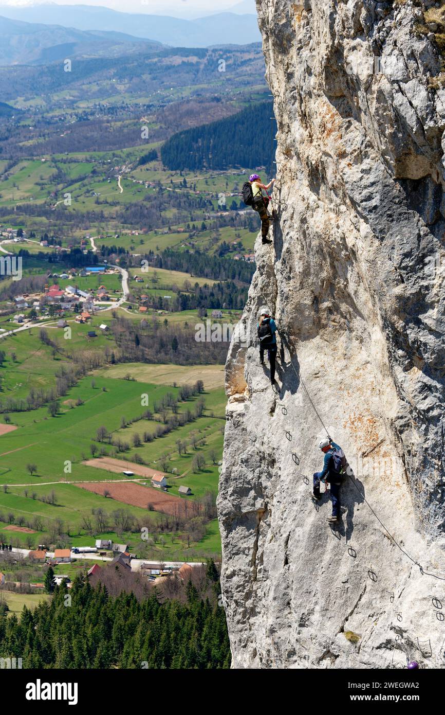 Persone che salgono via ferrata su una parete di roccia verticale. Vita sportiva in montagna. Scalatore che utilizza attrezzature adeguate per la sicurezza. Foto Stock