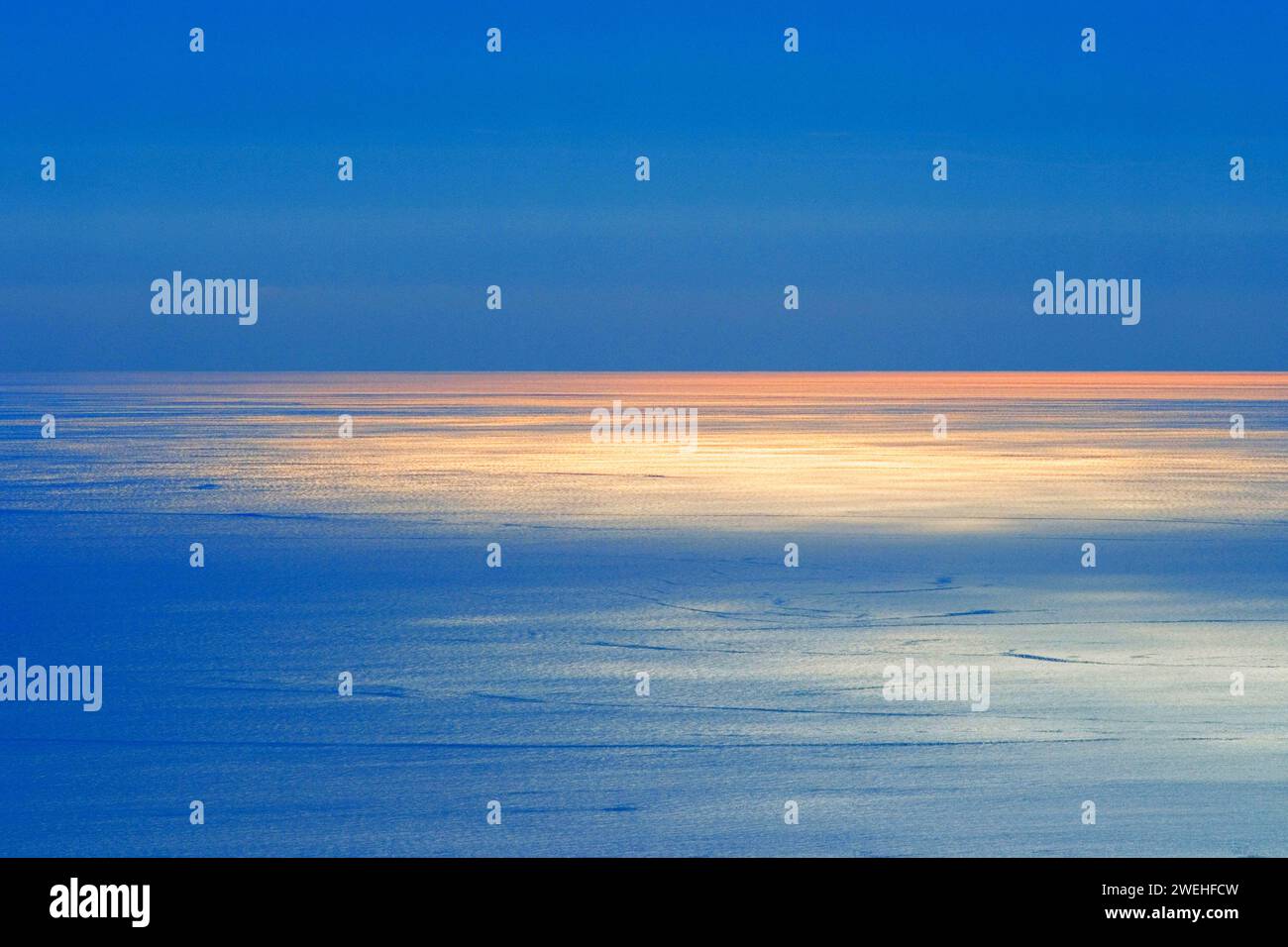 il sole rosso della sera si riflette sul mare Foto Stock