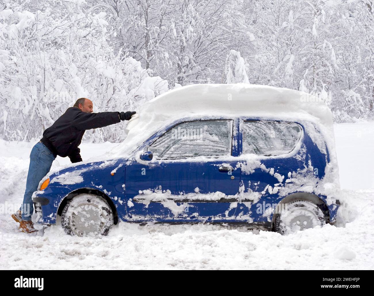 Un uomo libera la sua auto compatta blu da mezzo metro di neve fresca, Monaco di Baviera, CA. 2006, Baviera, Germania, Europa Foto Stock