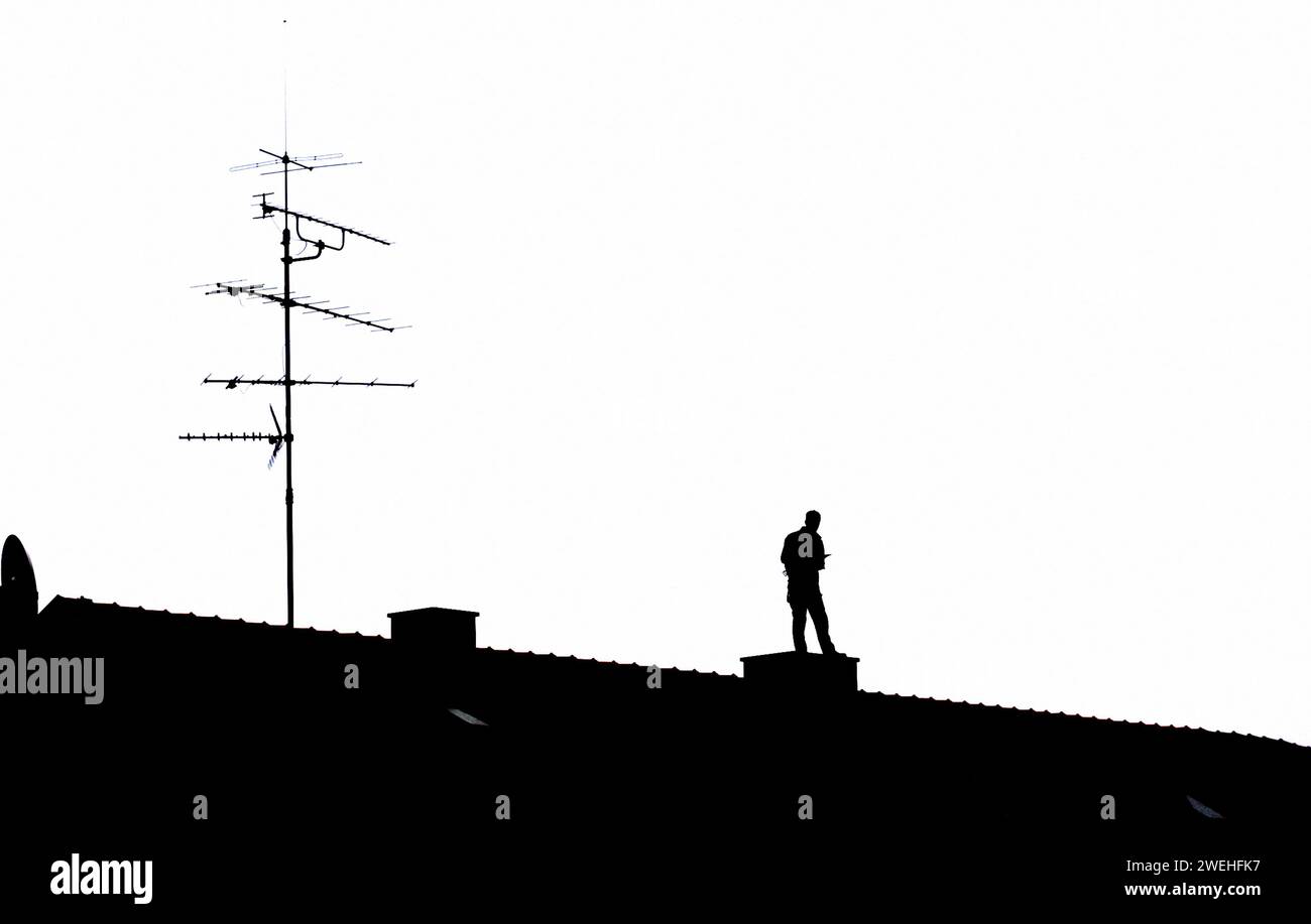 Un uomo si erge sul tetto di un condominio a Obergiesing e scrive qualcosa in un taccuino, silhouette, Monaco, Baviera, Germania Foto Stock