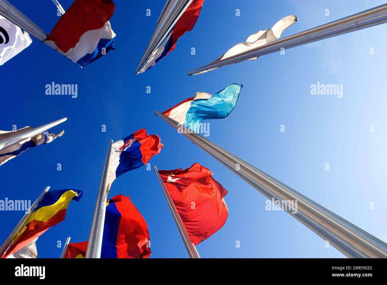 Ripresa grandangolare di bandiere nazionali europee, prospettiva rana, contro cielo blu, di fronte all'Ufficio europeo dei brevetti a Monaco, Baviera, Germania Foto Stock
