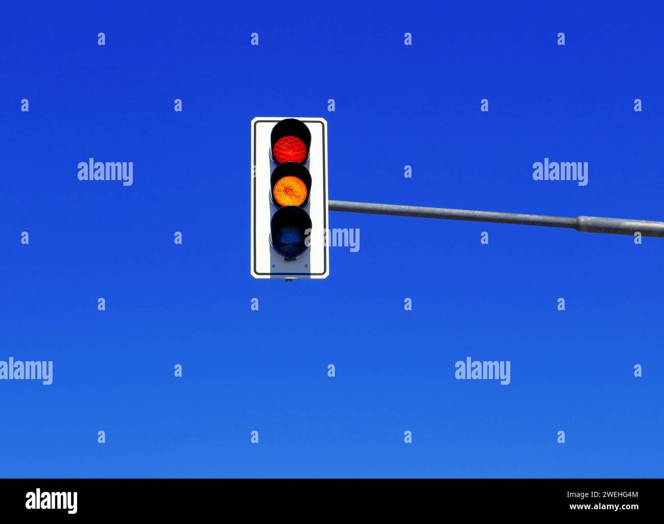 I semafori tedeschi mostrano ambra e rosso, contro un cielo blu Foto Stock