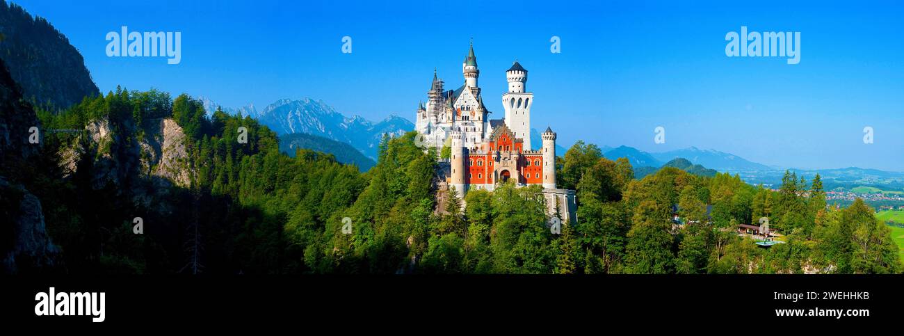 panorama del castello di neuschwanstein in una foresta verde con cielo blu al sole, Füssen, Baviera, Germania Foto Stock