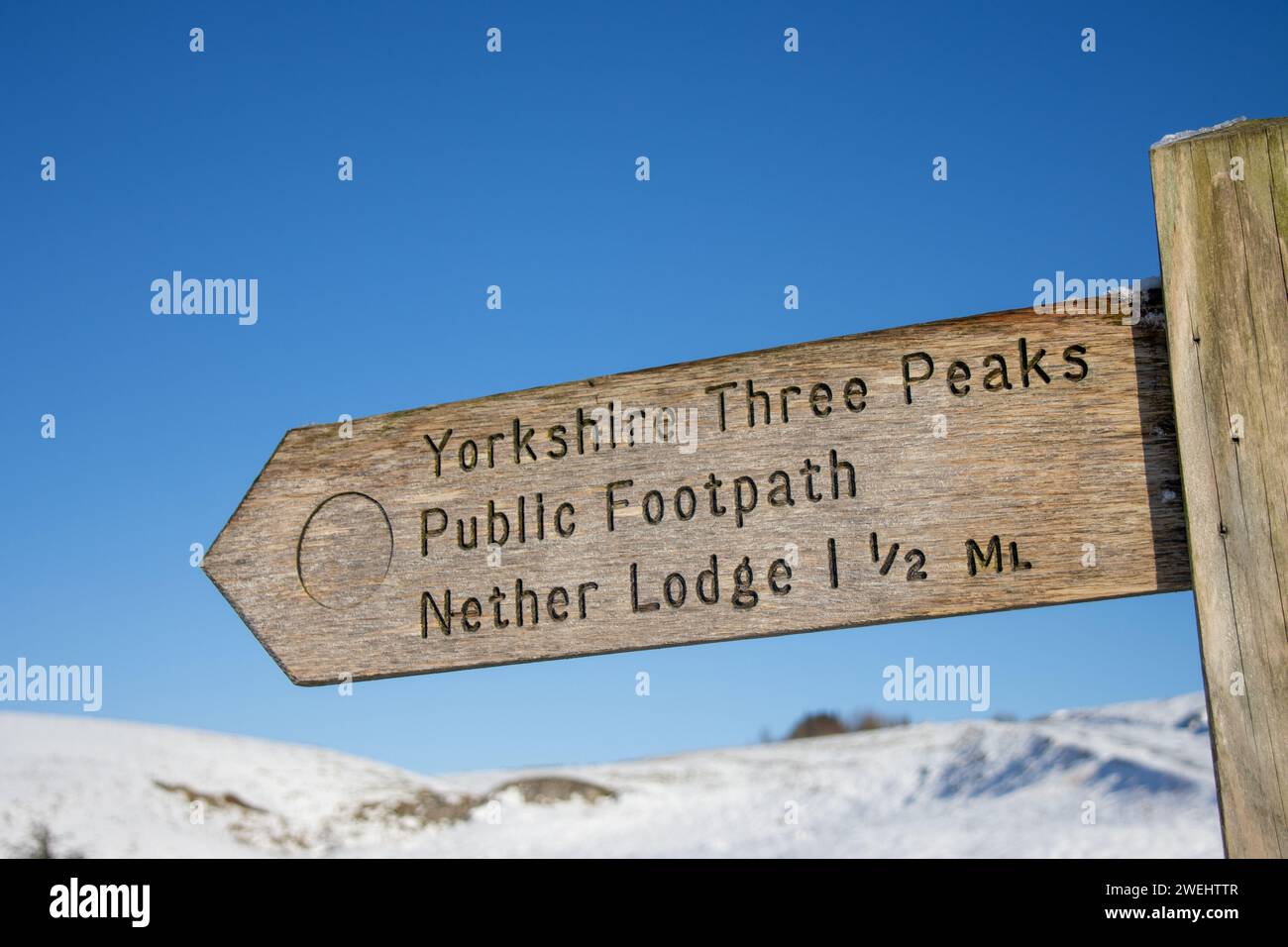 Un cartello di legno per lo Yorkshire Three Peaks, Public Footpath e Nether Lodge tra Pen-y-ghent e Whernside nelle Yorkshire Dales in inverno. Foto Stock