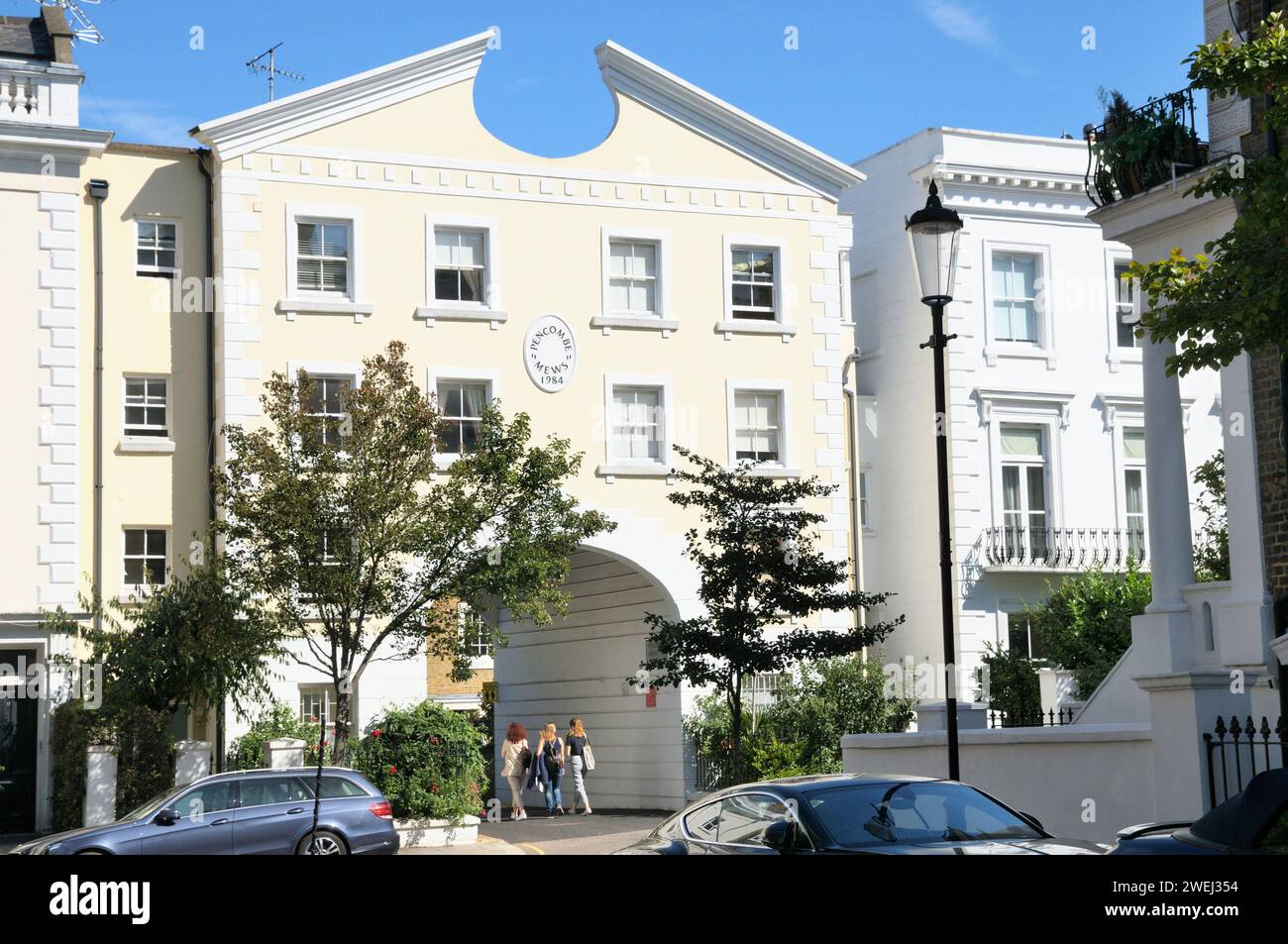 Tre giovani donne che camminano attraverso l'arcata d'ingresso di Pencombe Mews, Notting Hill, Kensington e Chelsea, West London, W11, Inghilterra Regno Unito Foto Stock