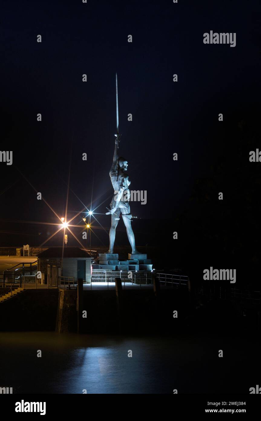 Statua "Verity" dell'artista di fama mondiale Damien Hirst illuminata di notte sul molo all'ingresso del porto di Ilfracombe, North Devon, Inghilterra, Regno Unito Foto Stock