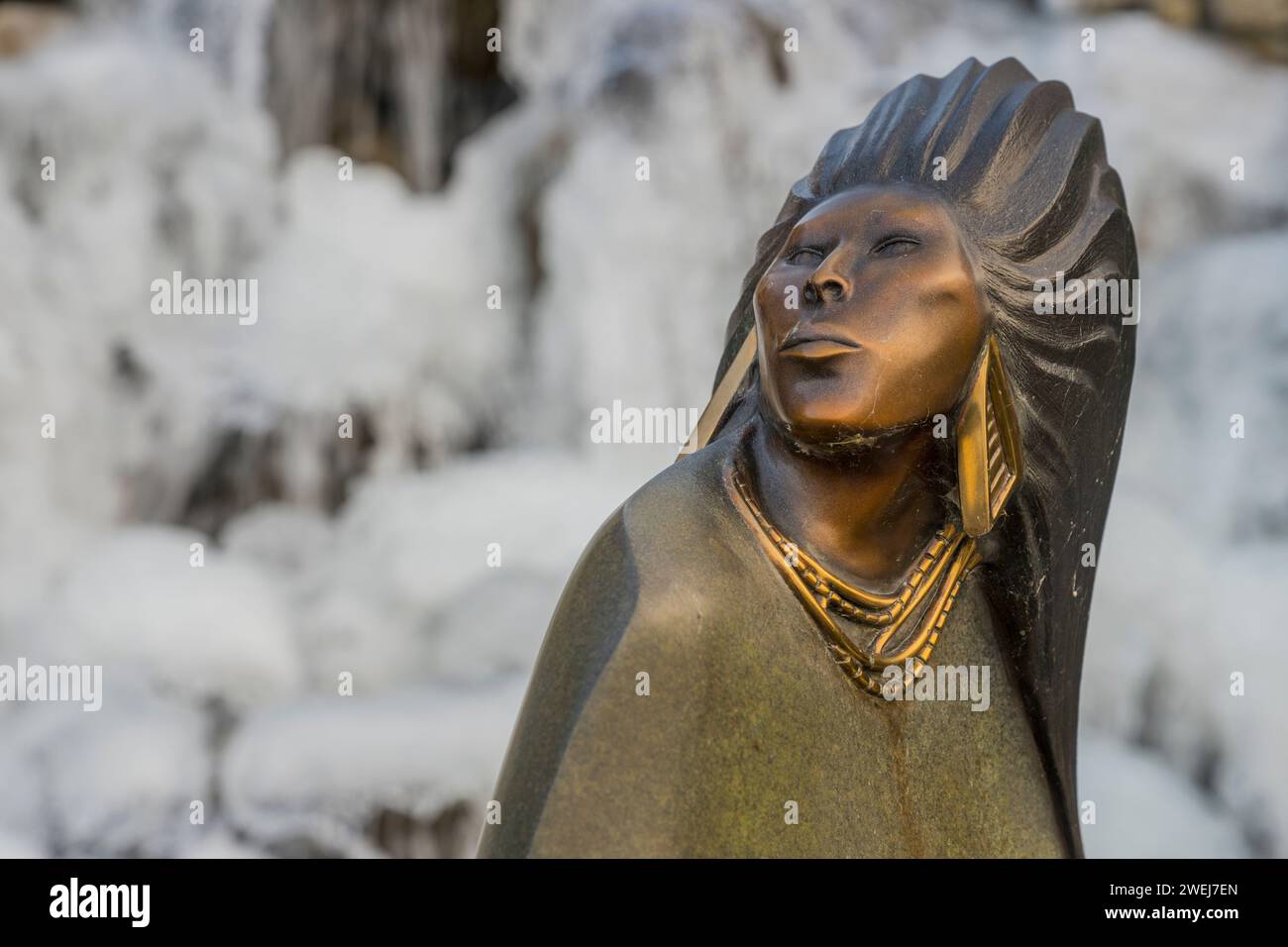 Una statua di bronzo in inverno che si trova in una fontana d'acqua ghiacciata nel giardino dei condomini Shumway a Kirkland, nello stato di Washington, USA. Foto Stock