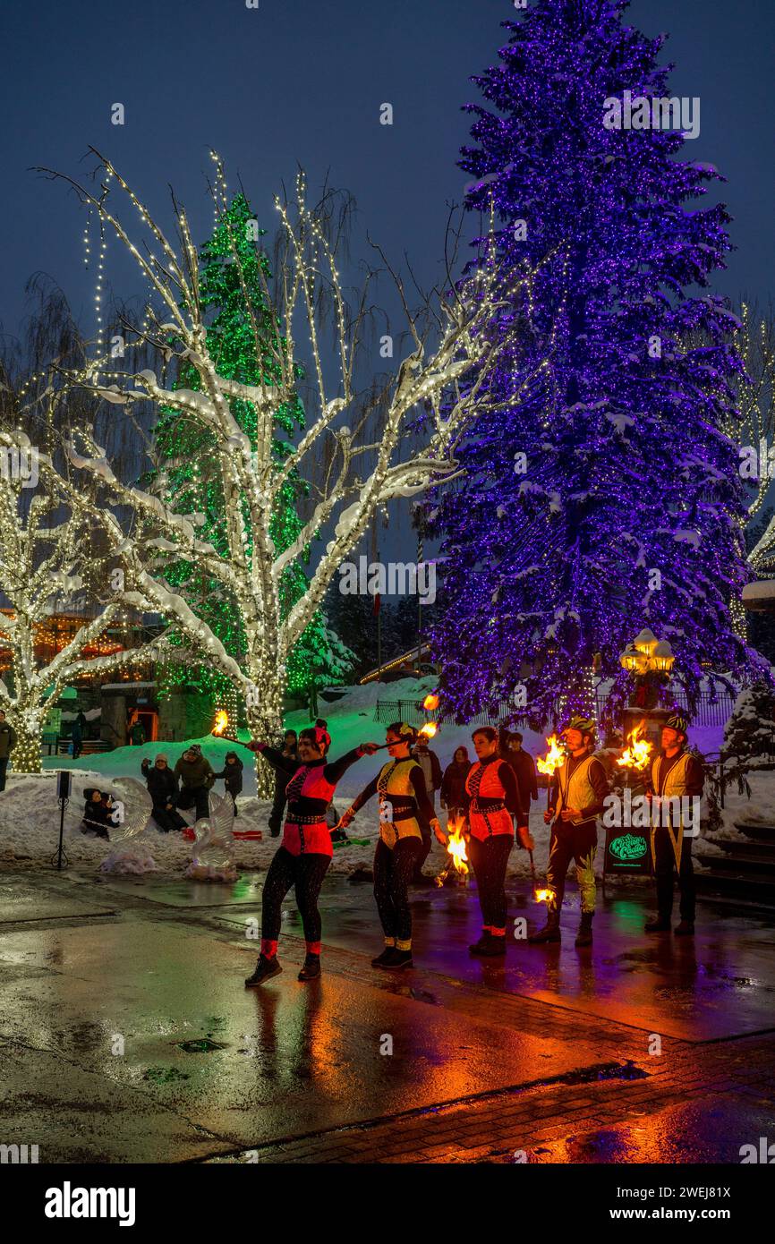 Una performance di danza del fuoco del Cirque Cadia, una troupe di artisti circensi, come parte del Carnevale invernale, sotto i colorati alberi illuminati di Leavenworth, che Foto Stock