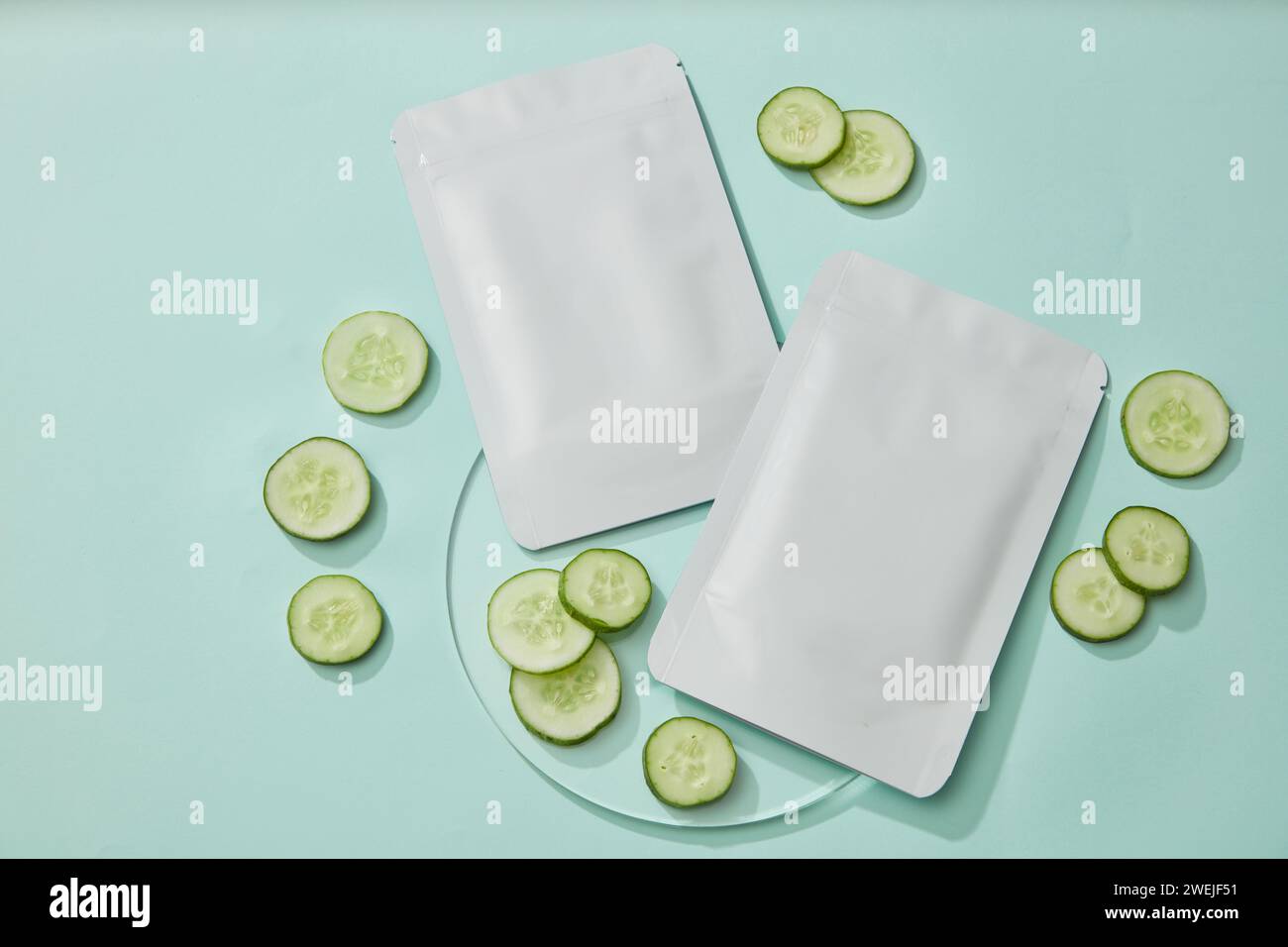 Pacchetto mascherine facciali con maschera di cetriolo e fette di cetriolo fresco decorate su sfondo pastello. Cumbo antiossidante, anti-invecchiamento e di protezione UV Foto Stock