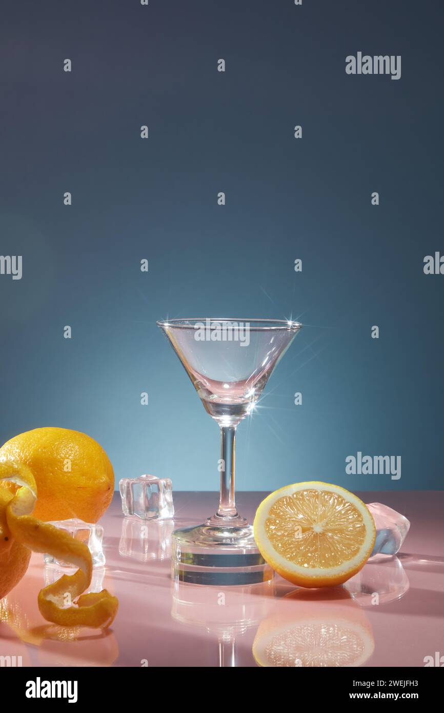 Tazza di vetro con ghiaccio e limoni freschi decorata su sfondo blu scuro. Scena per pubblicizzare prodotti per bevande con gusto di limone fresco per un rinfresco Foto Stock