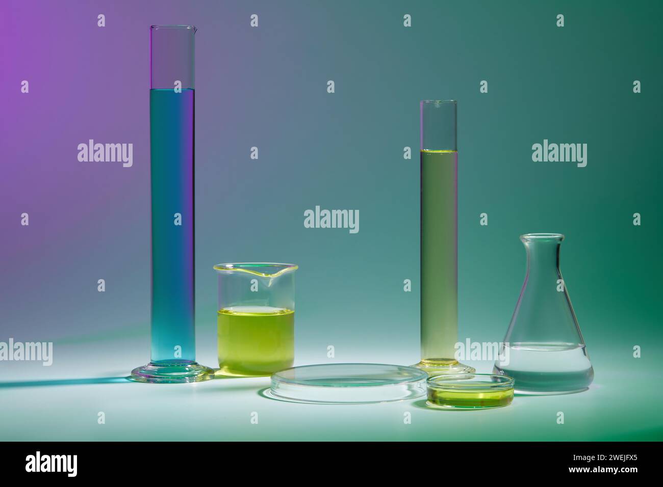 Sfondo astratto con concetto di laboratorio - vetreria da laboratorio contenente liquido colorato e podio trasparente rotondo per la presentazione del prodotto cosmetico Foto Stock