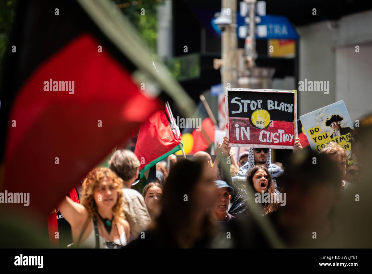 26 gennaio 2024, Melbourne, Australia. Un manifestante tiene un cartello con la scritta "Stop Black Death in Custody" mentre marciano con circa 30.000 altri manifestanti che stavano radunando contro l'Australia Day, o Invasion Day. Crediti: Jay Kogler/Alamy Live News Foto Stock