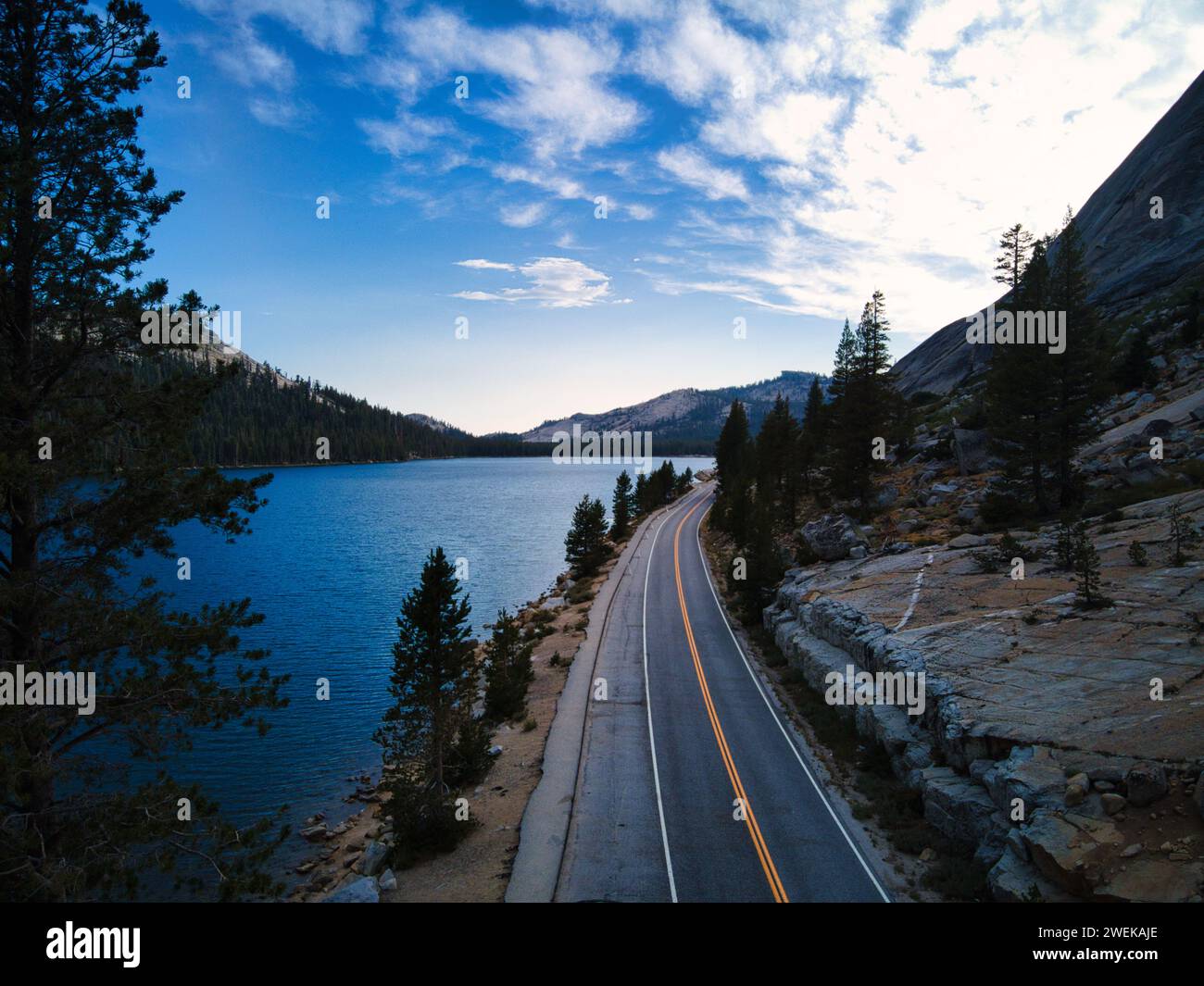 Il tramonto su un lago tranquillo mentre una strada scompare all'orizzonte Foto Stock