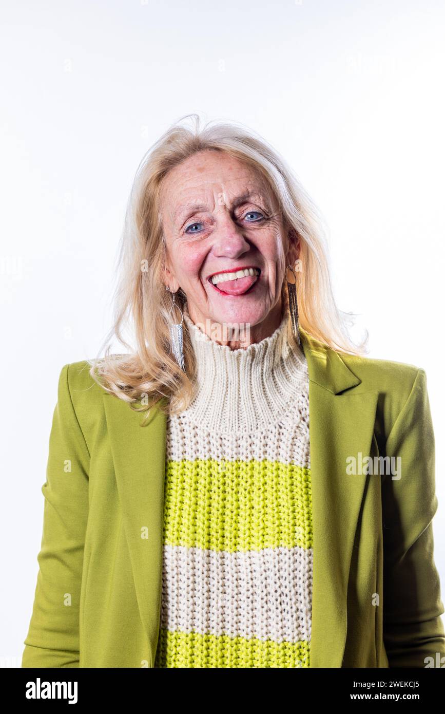 Questa immagine è una rappresentazione genuina di una donna anziana catturata in un momento di esuberanza. Il suo sorriso aperto e sincero e gli occhi vivaci riflettono una felicità interiore e un personaggio giocoso. I colori vivaci e allegri del suo outfit aggiungono al senso generale di calore e vivacità che la contraddistingue. Questa fotografia cattura meravigliosamente lo spirito di una persona che ama la vita con entusiasmo e apertura. Esuberante Senior Lady's Candid Moment. Foto di alta qualità Foto Stock