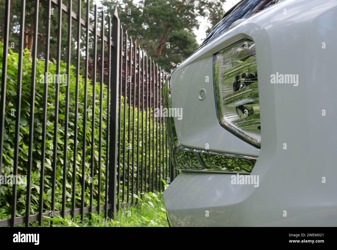 Paraurti anteriore dell'auto parcheggiato nella recinzione anteriore in metallo presso il parcheggio all'aperto Foto Stock