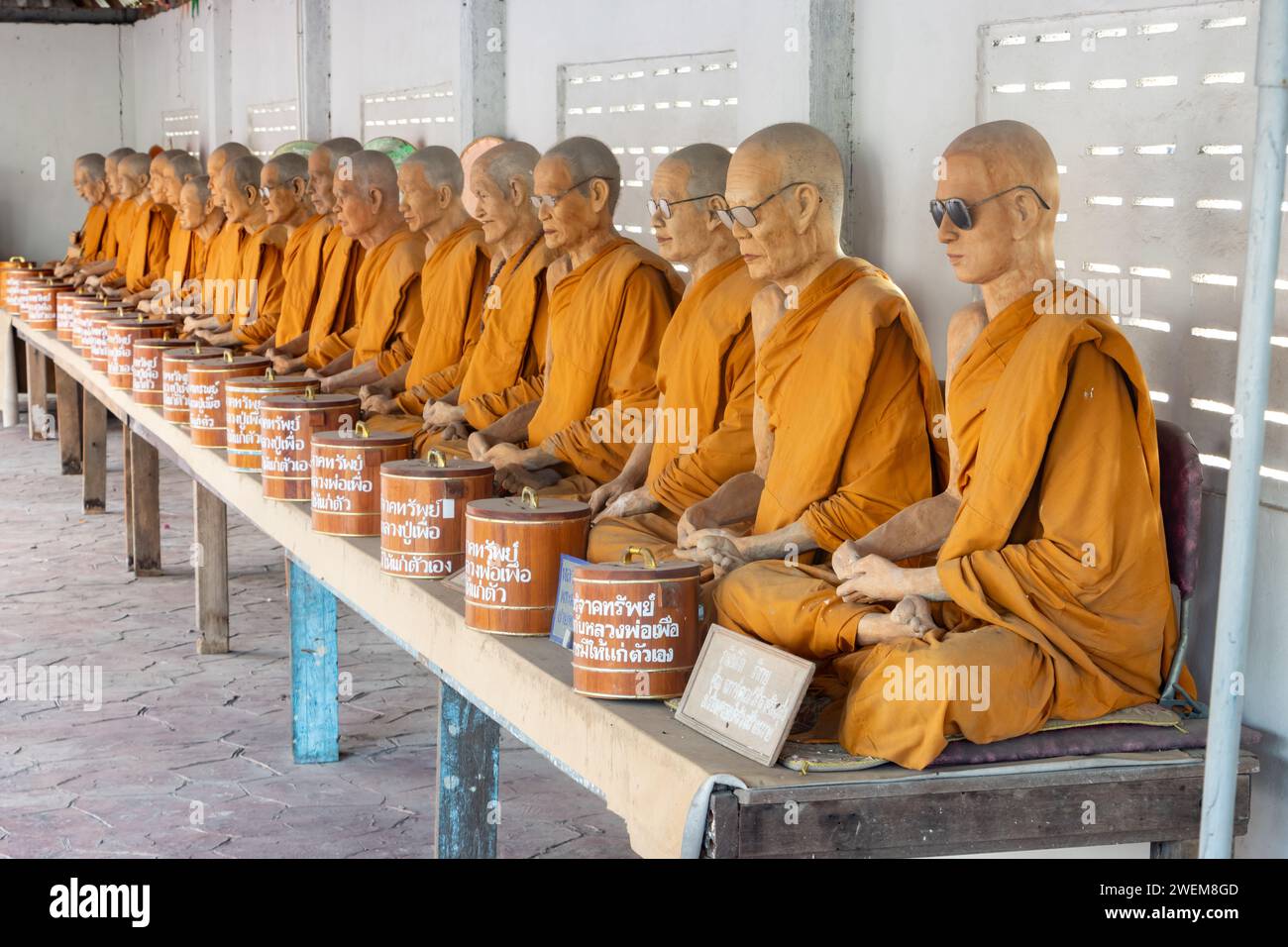 SAMUT SAKHON, THAILANDIA, DEC 03 2023, Una fila di statue di cera di monaci buddisti seduti in un tempio buddista Foto Stock