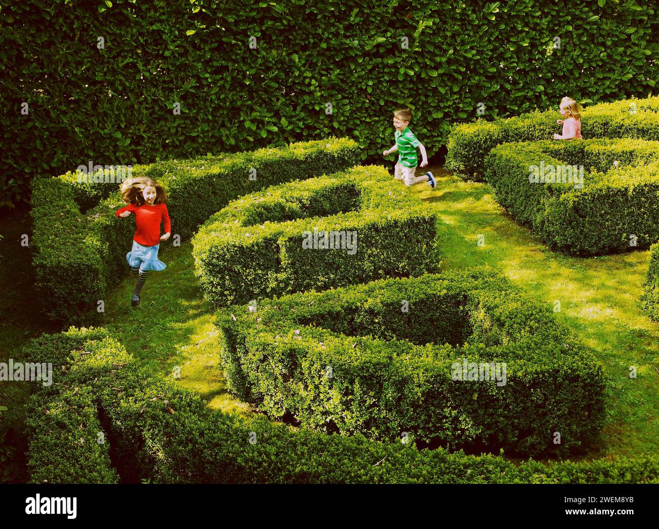 I bambini in esecuzione nel giardino labirinto Foto Stock
