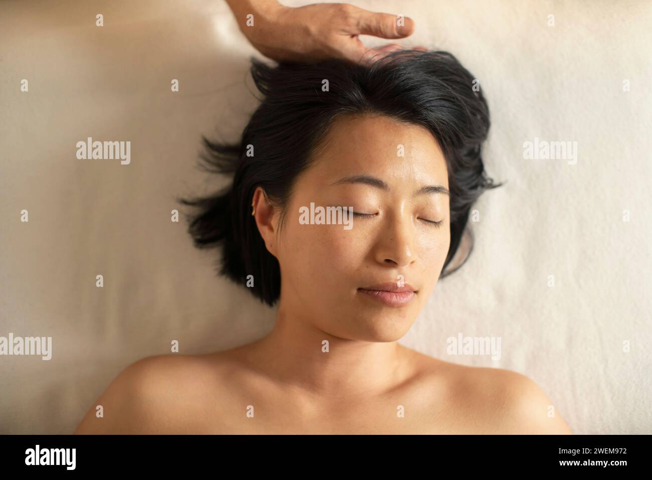 Vista dall'alto, donna tranquilla che riceve un massaggio alla testa nella spa Foto Stock