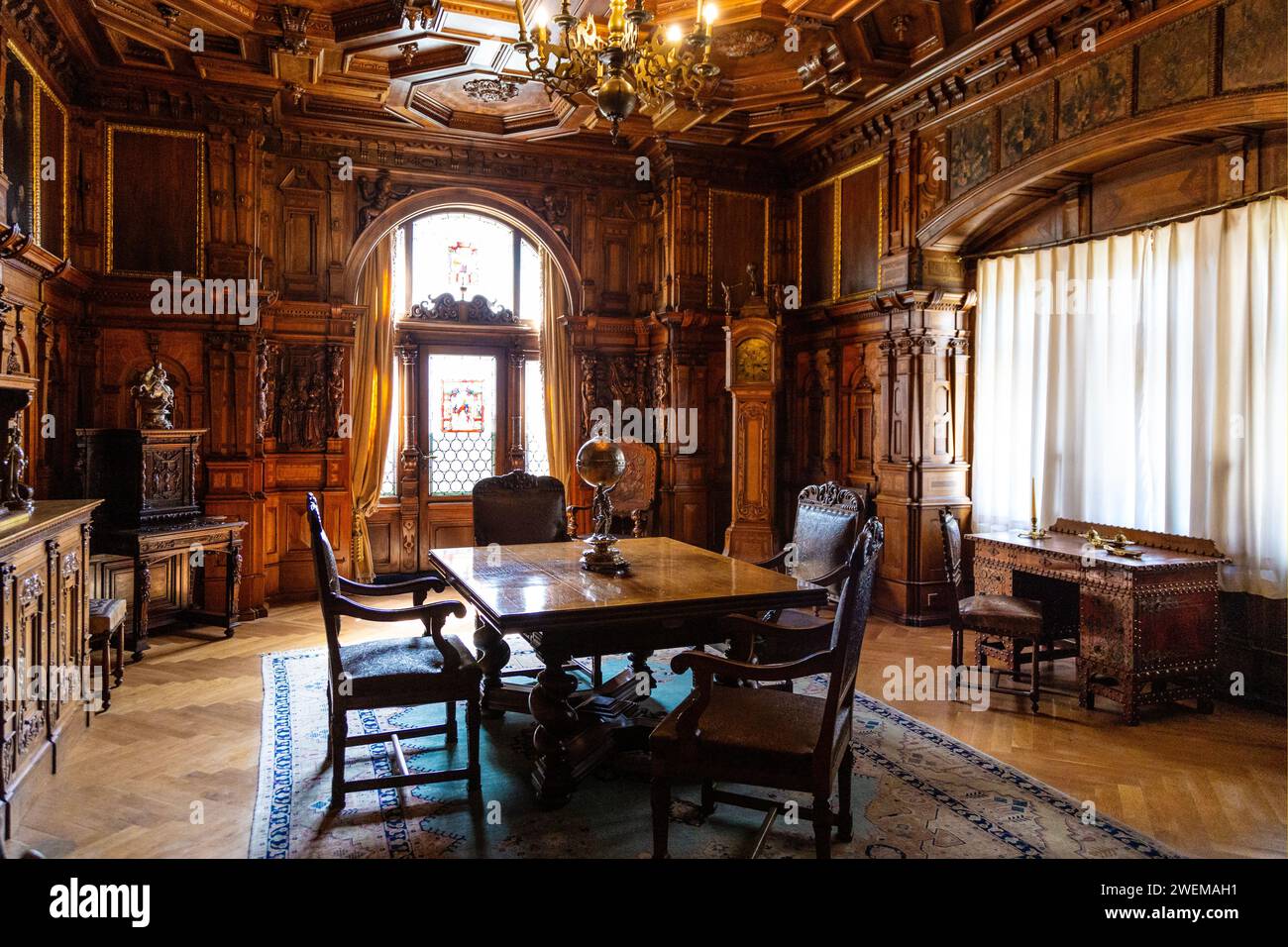 Sala consiliare con pannelli in legno, tavolo e sedie al Castello di Peles, Sinaia, Romania Foto Stock