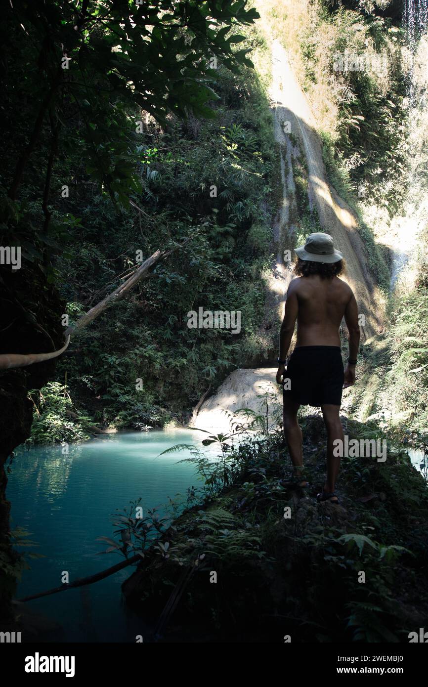 Turista maschile che indossa un cappello, guardando una cascata turchese Foto Stock