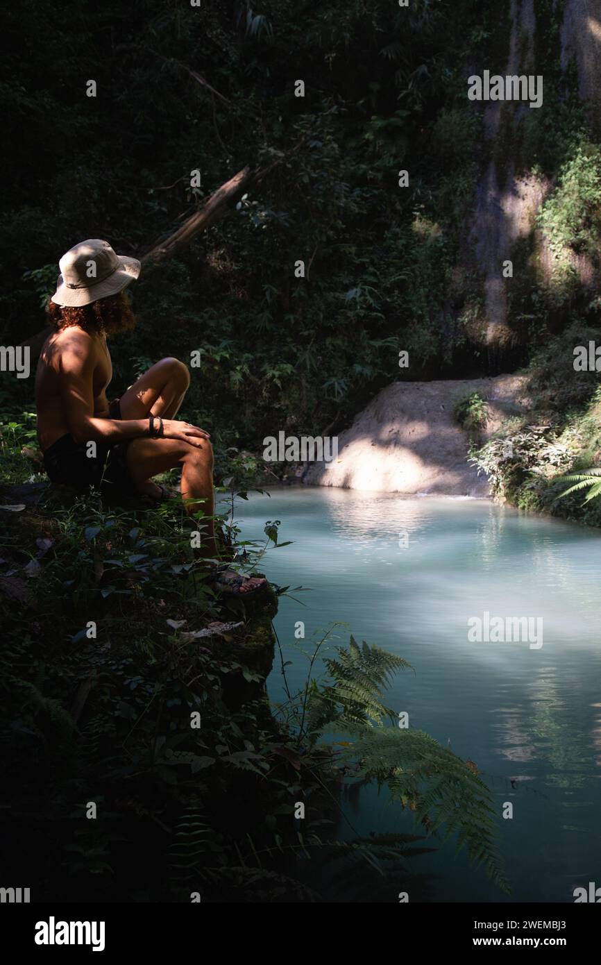Turista maschile che indossa un cappello, guardando uno stagno d'acqua turchese Foto Stock