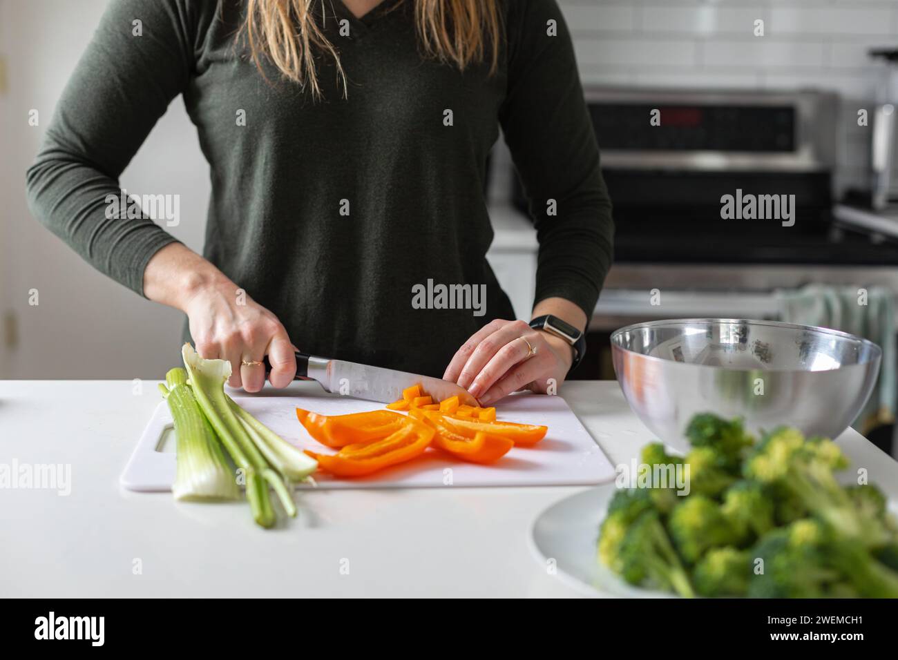 donna che affetta verdure fresche in cucina Foto Stock