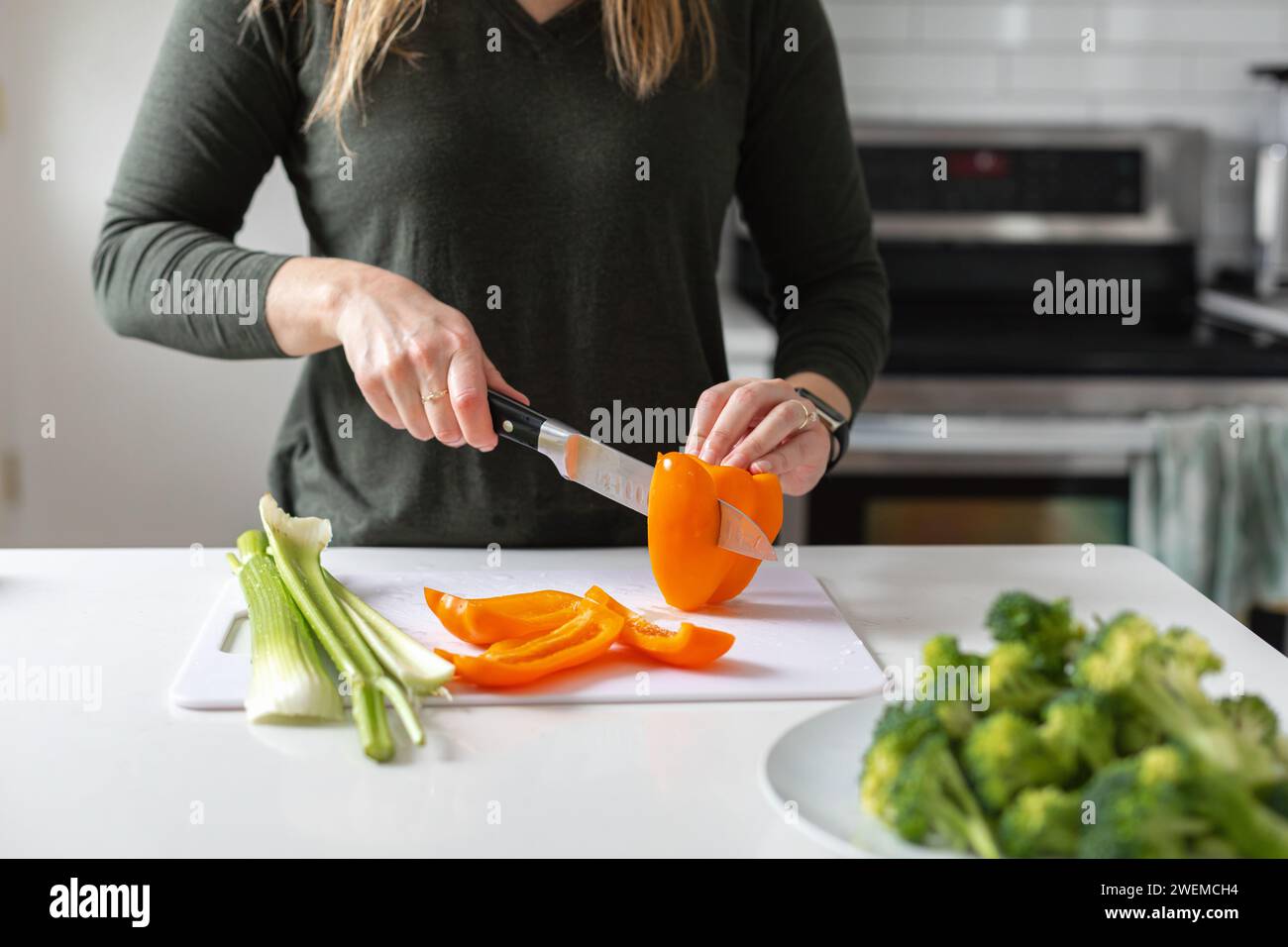 affettare un peperone d'arancia per una cena vegana Foto Stock