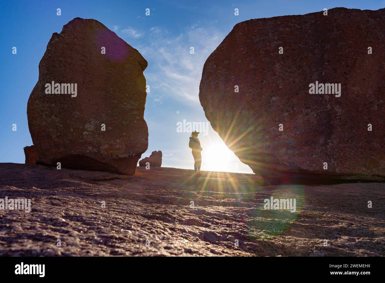Escursionista con scoppio di sole, vicino a massi sulla cima del sentiero in Texas Foto Stock