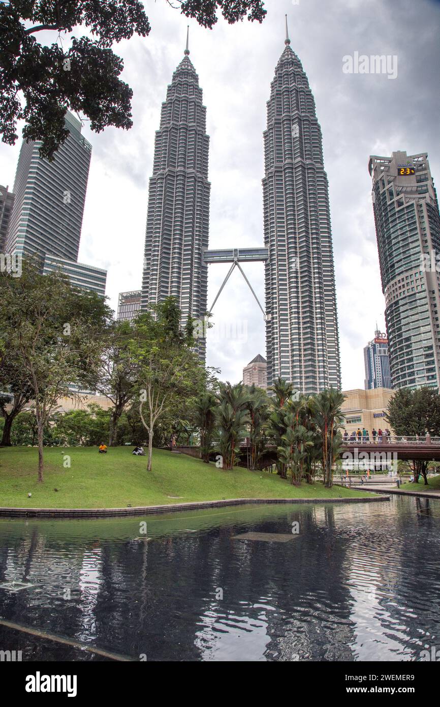 Persone al parco, sotto le Petronas Towers durante una giornata nuvolosa Foto Stock