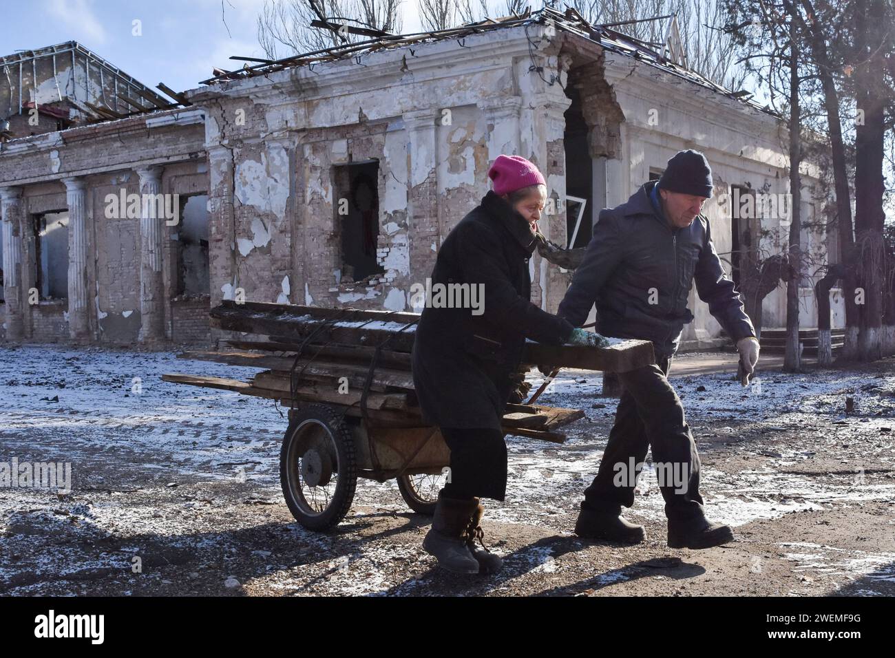 Una coppia anziana che trasporta le tavole di legno sulla carriola vicino allo storico edificio municipale che è stato pesantemente danneggiato dai bombardamenti russi a Orikhiv. Orikhiv è una piccola città vicino a Zaporizhzhia, che funge da ultimo pilastro di resistenza per i soldati dell'esercito ucraino nel sud, mentre le forze armate russe continuano ad avanzare verso la Robotyne liberata. I cittadini di Orikhiv, che ospitano circa 700 persone, rischiano la vita sopportando quotidianamente la bomba aerea e gli attacchi di artiglieria mentre lottano per sopravvivere. (Foto di Andriy Andriyenko/SOPA Images/Sipa USA) Foto Stock
