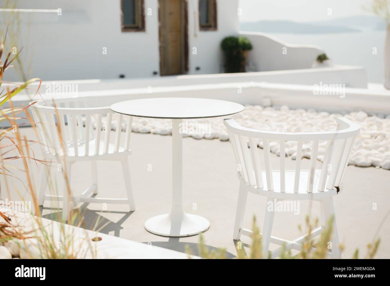 Terrazza con sedie bianche e tavolo con vista sulla costa di Oia Foto Stock