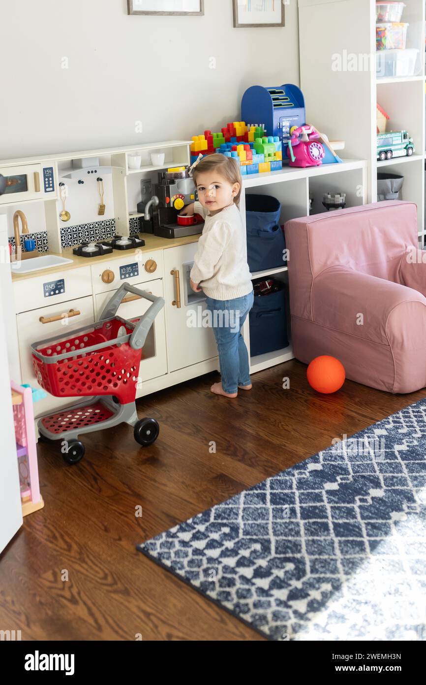 La bambina fa finta di giocare con il suo set da cucina Foto Stock